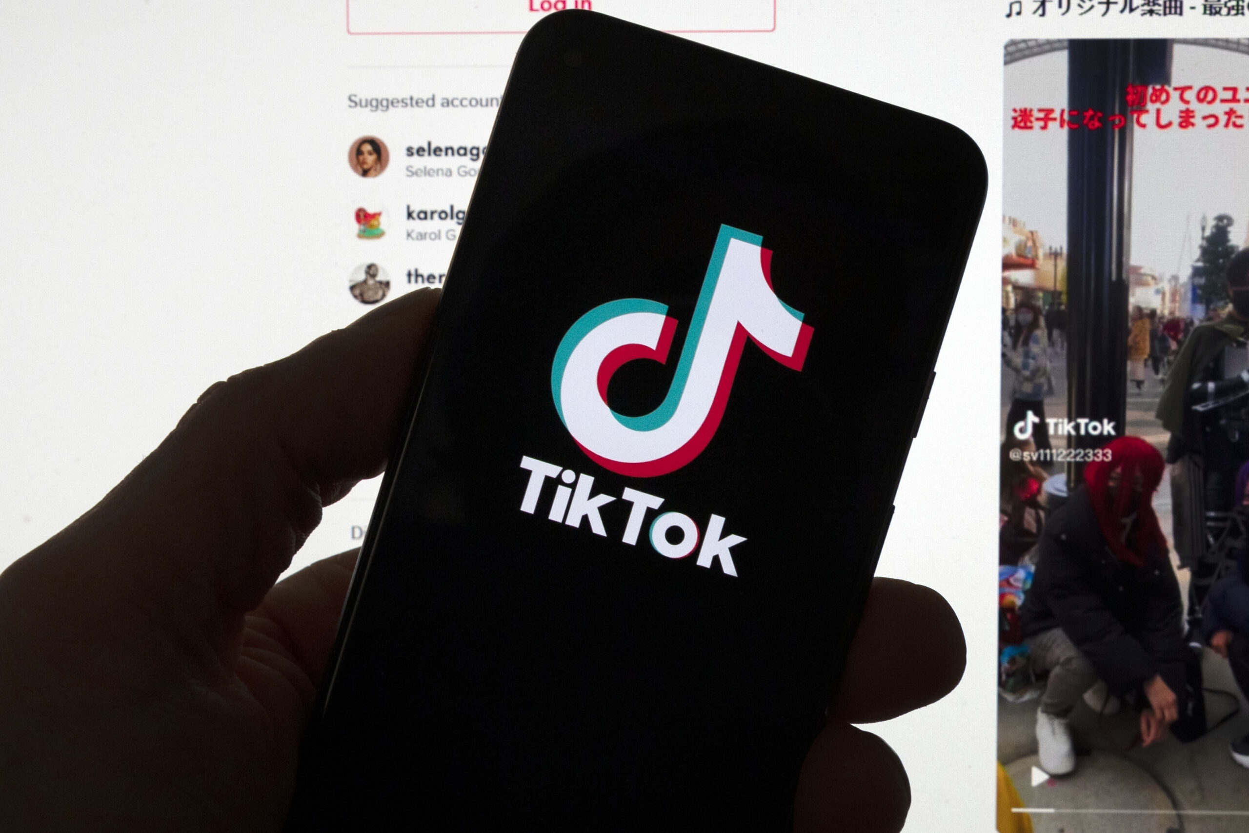 FILE - The TikTok logo is seen on a mobile phone in front of a computer screen which displays the T...