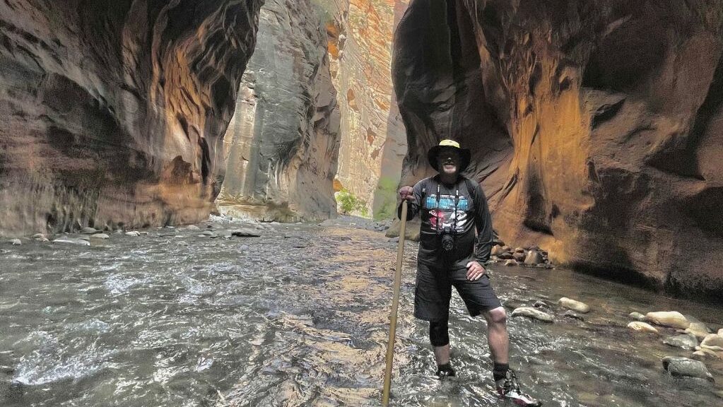 tim hughes is pictured in the narrows at zion national park...