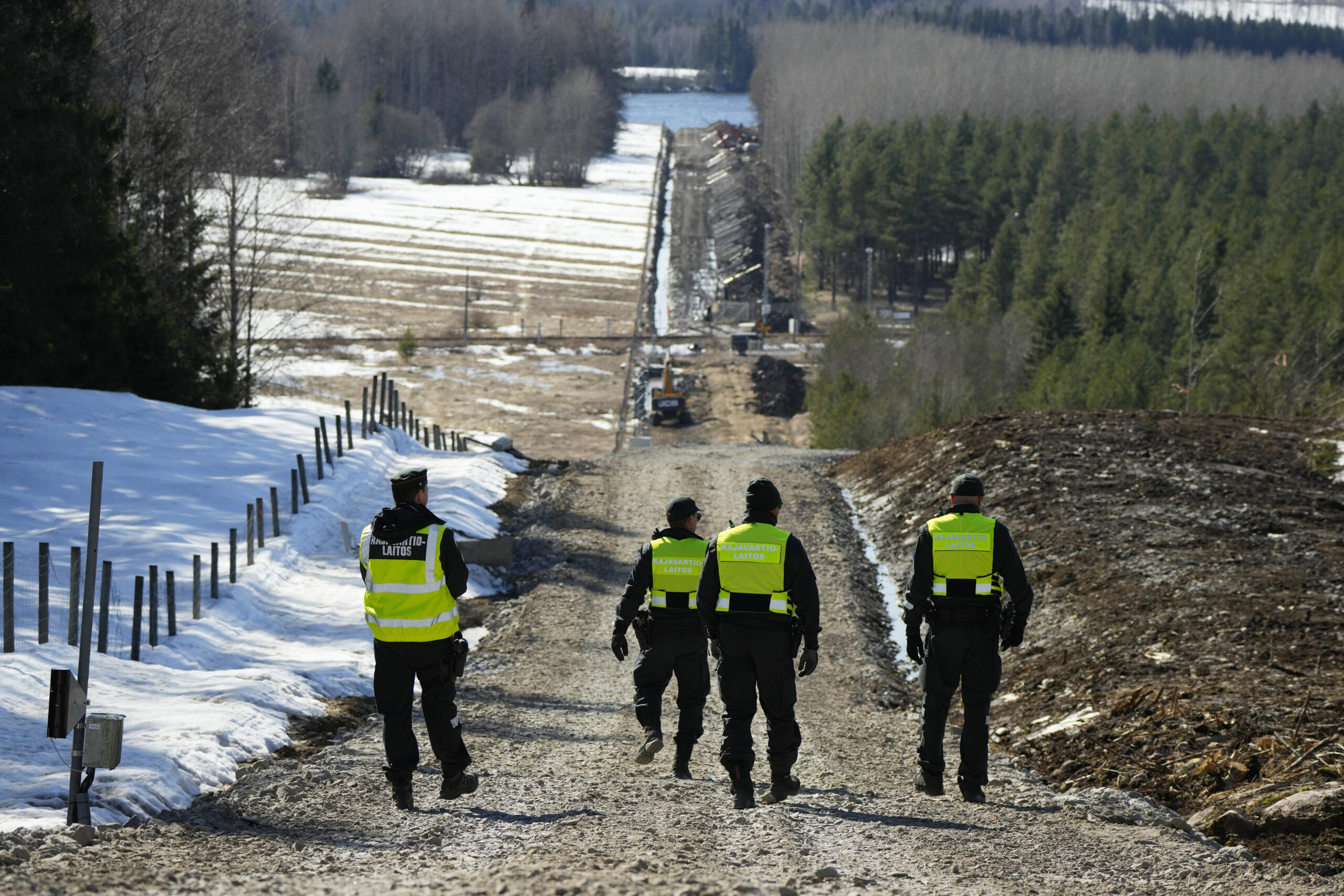 Finland's border guards walk at construction site of the border barrier fence between Finland and R...