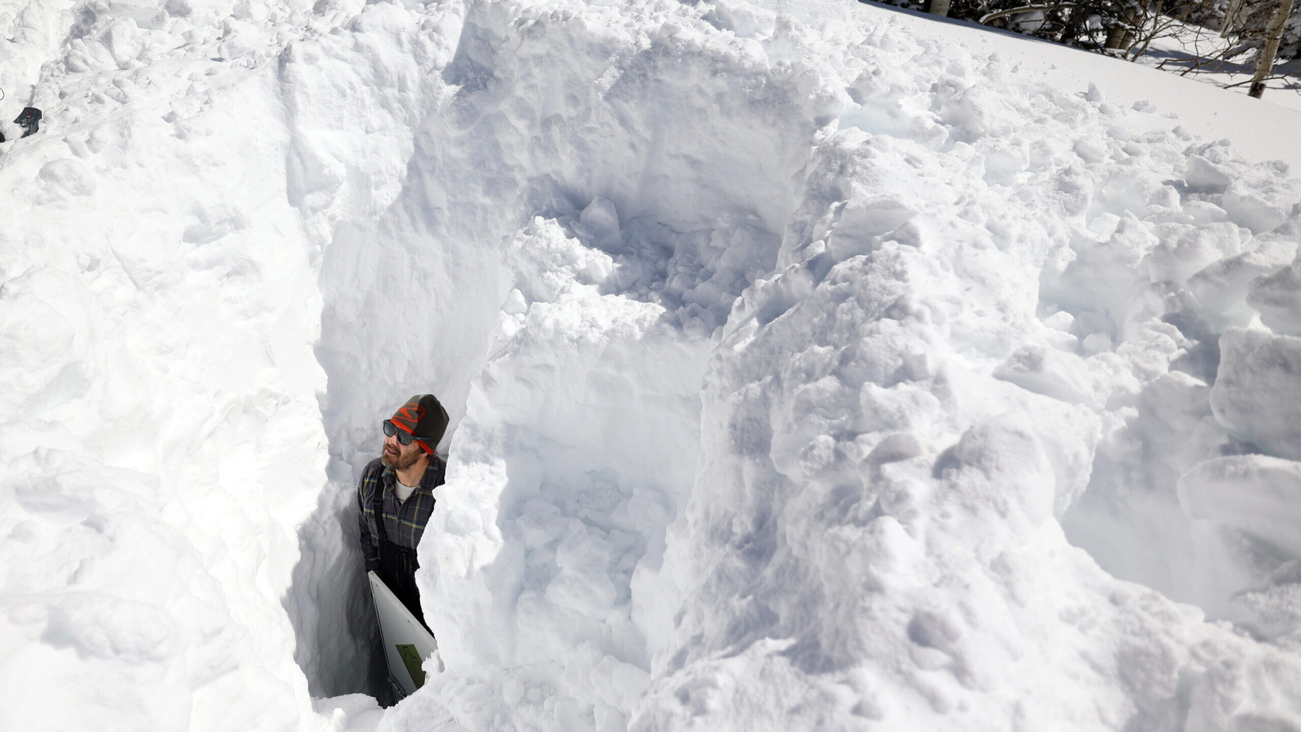 man with shovel demonstrates depth of utah snowpack...