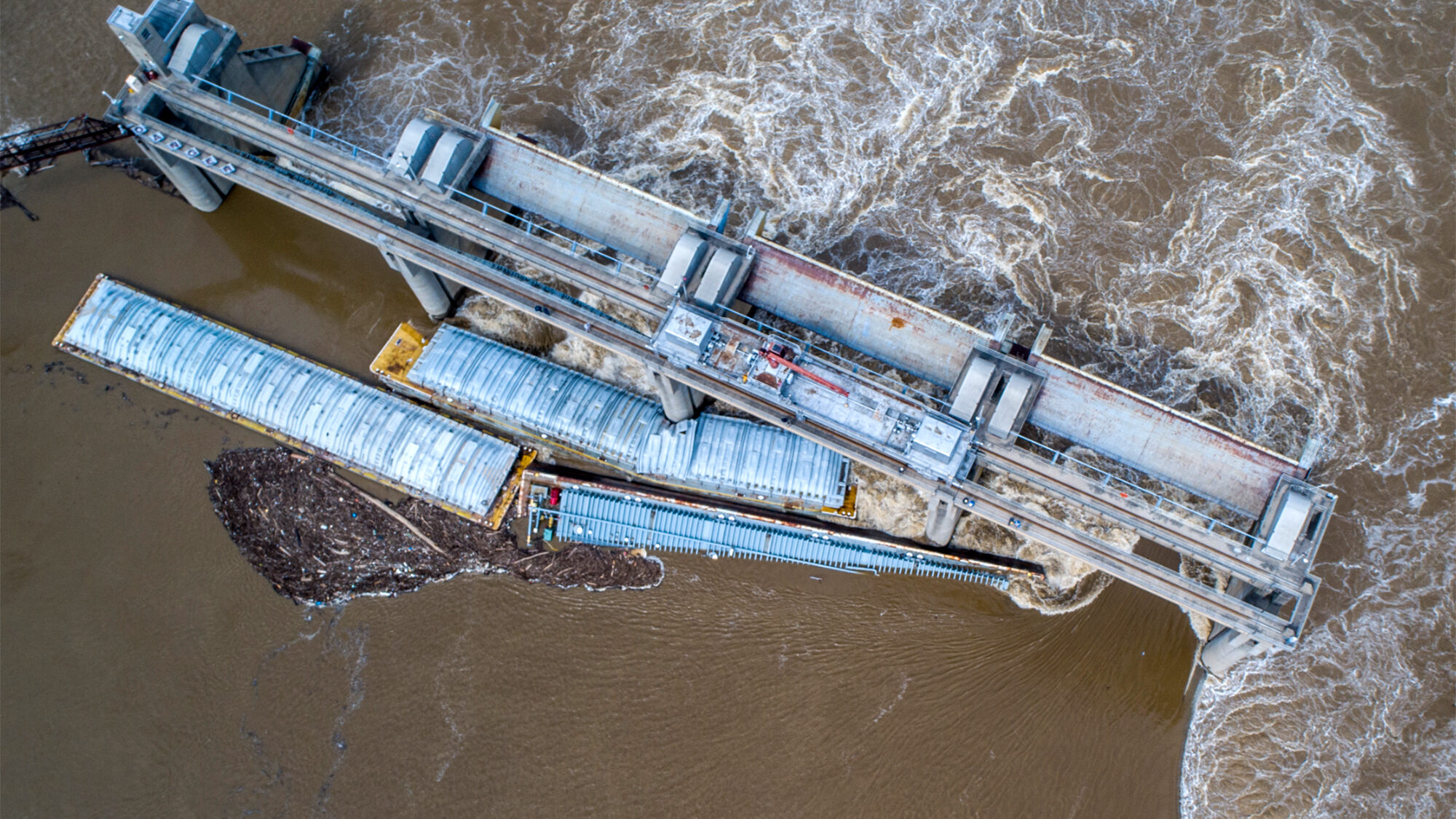 Two barges are seen stuck in the Ohio River; one has been removed, while the other remains. Mandato...