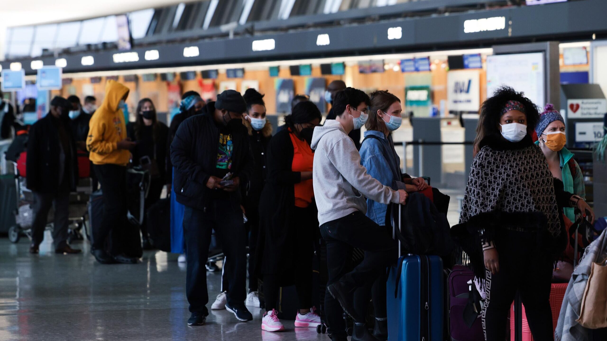 Passengers wait in line to check in for their flights at the Dulles International Airport in Dulles...