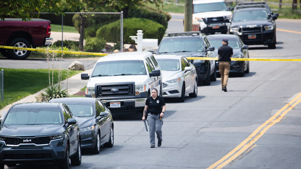 Layton Police officers walk down the street at the scene of a triple homicide in Layton on May 19, ...