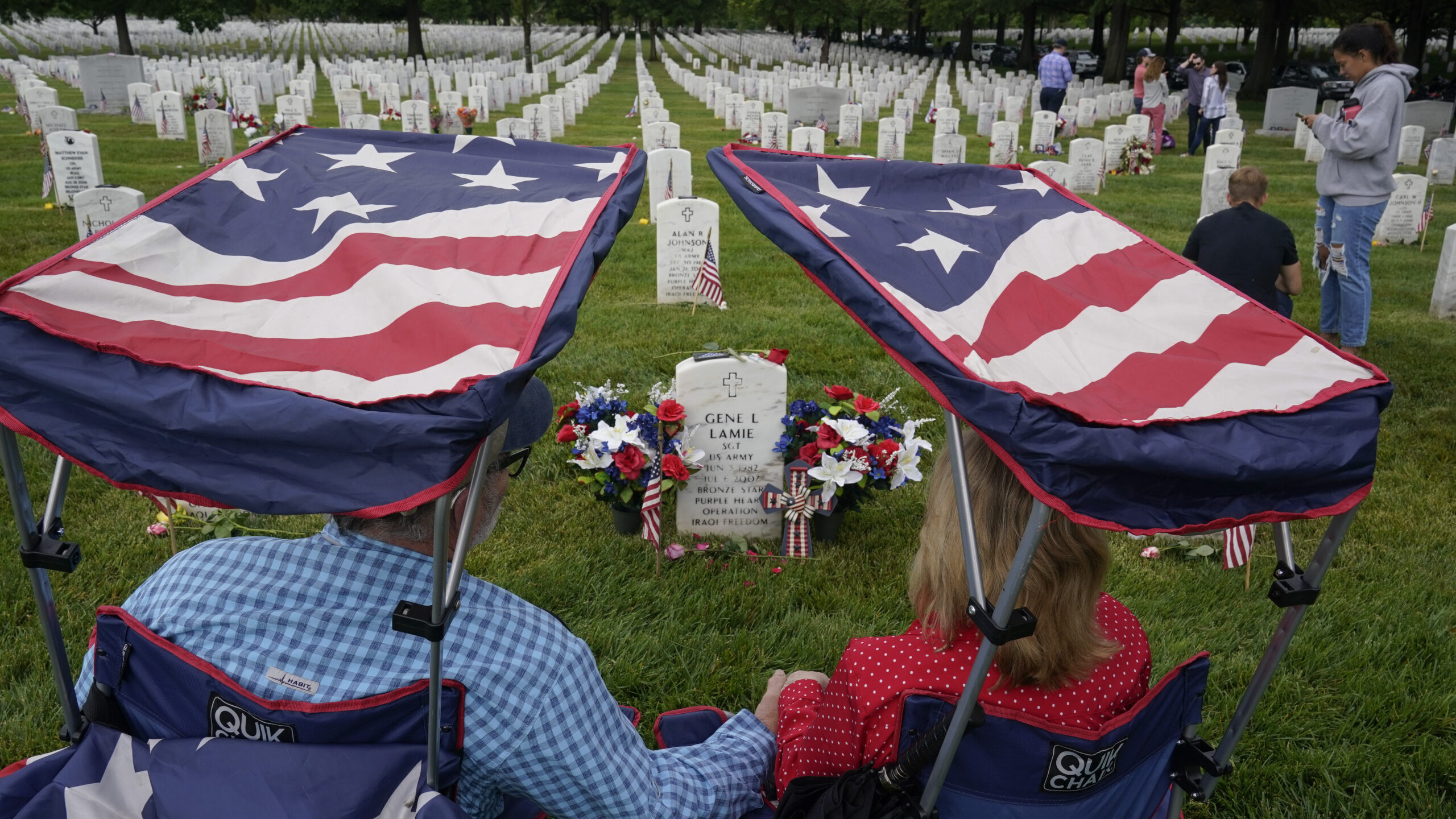 two people sit by their son's grave on memorial day...