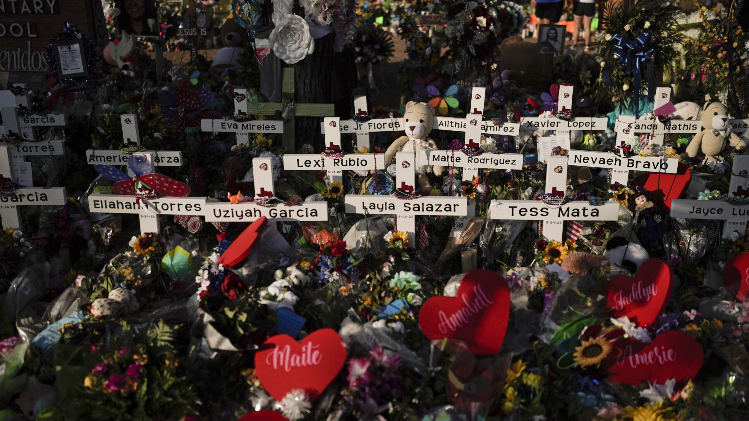 FILE - Flowers are piled around crosses with the names of the victims killed in a school shooting a...