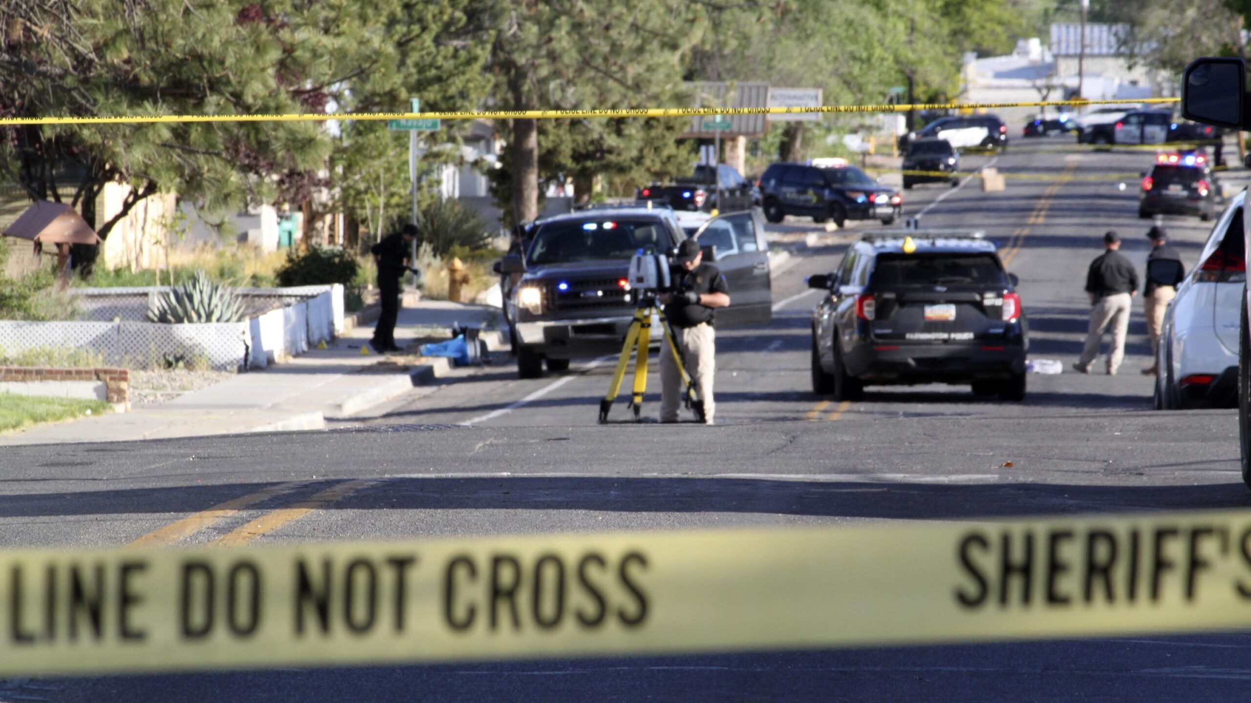 Investigators work along a residential street following a deadly shooting on May 15, in Farmington,...