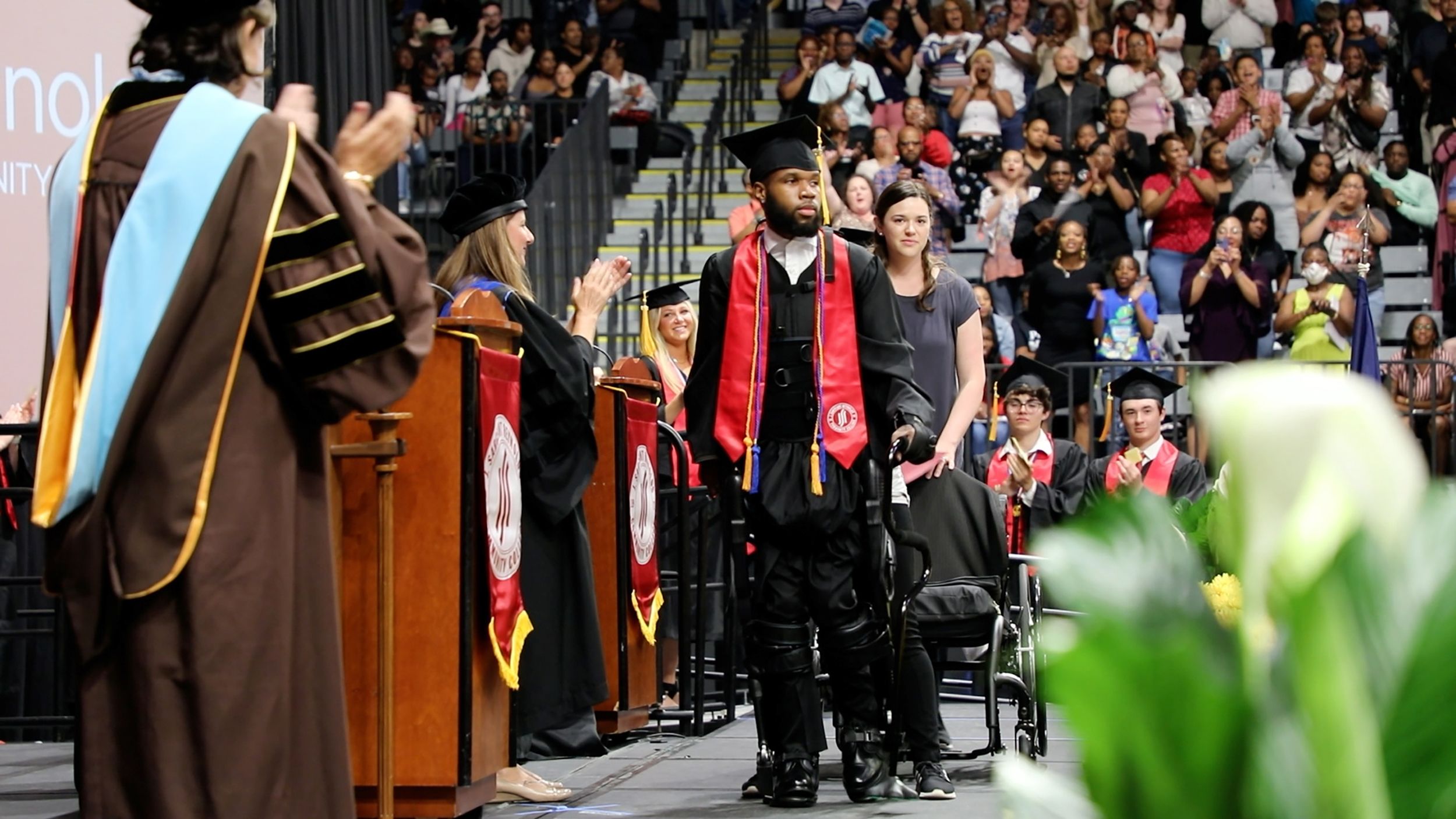 Khalil Watson uses an exoskeleton to stand and walk at his college graduation ceremony years after ...