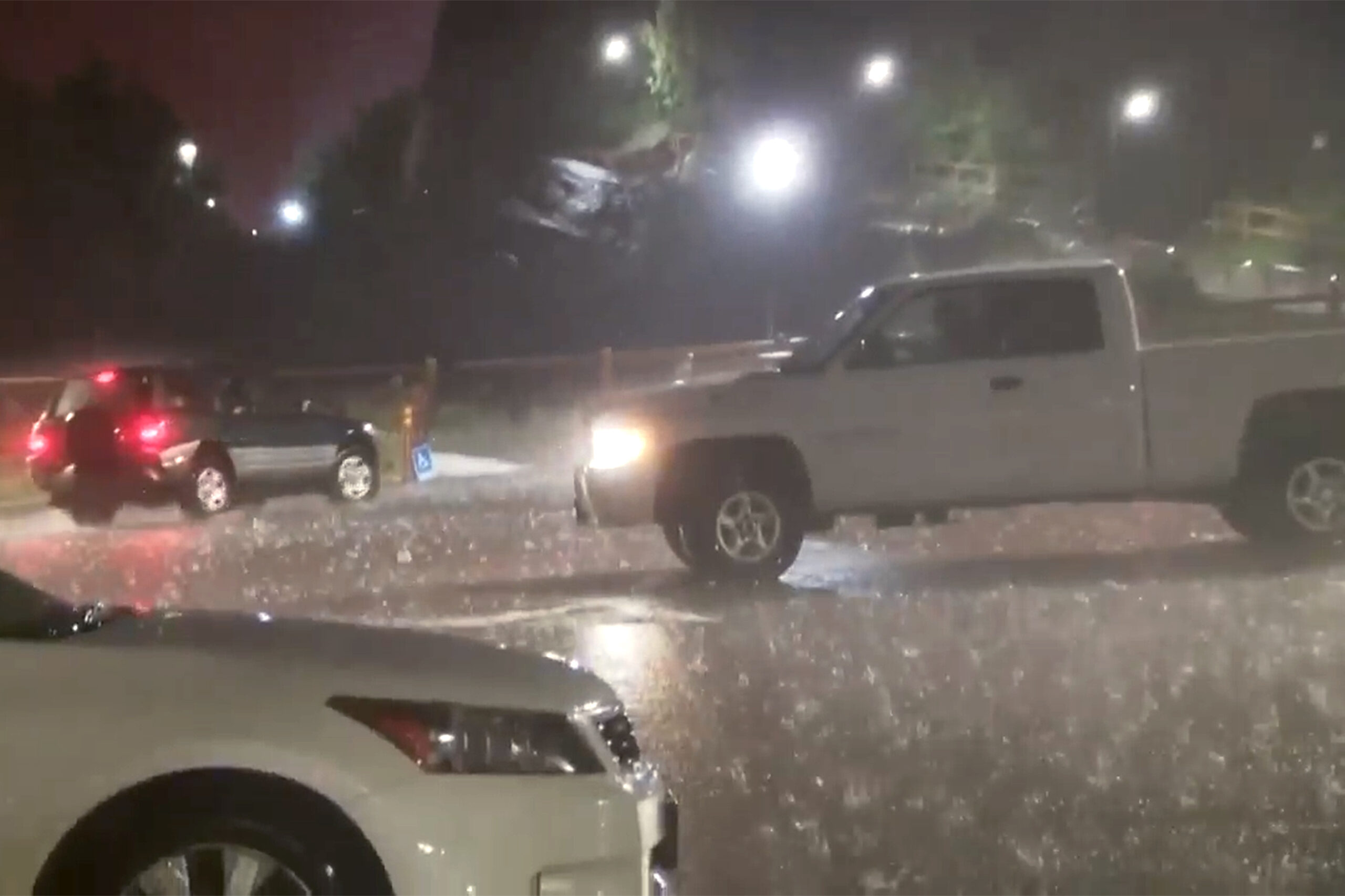 In this image taken from video, hail fails on vehicles during a storm at the Red Rocks Ampitheatre,...