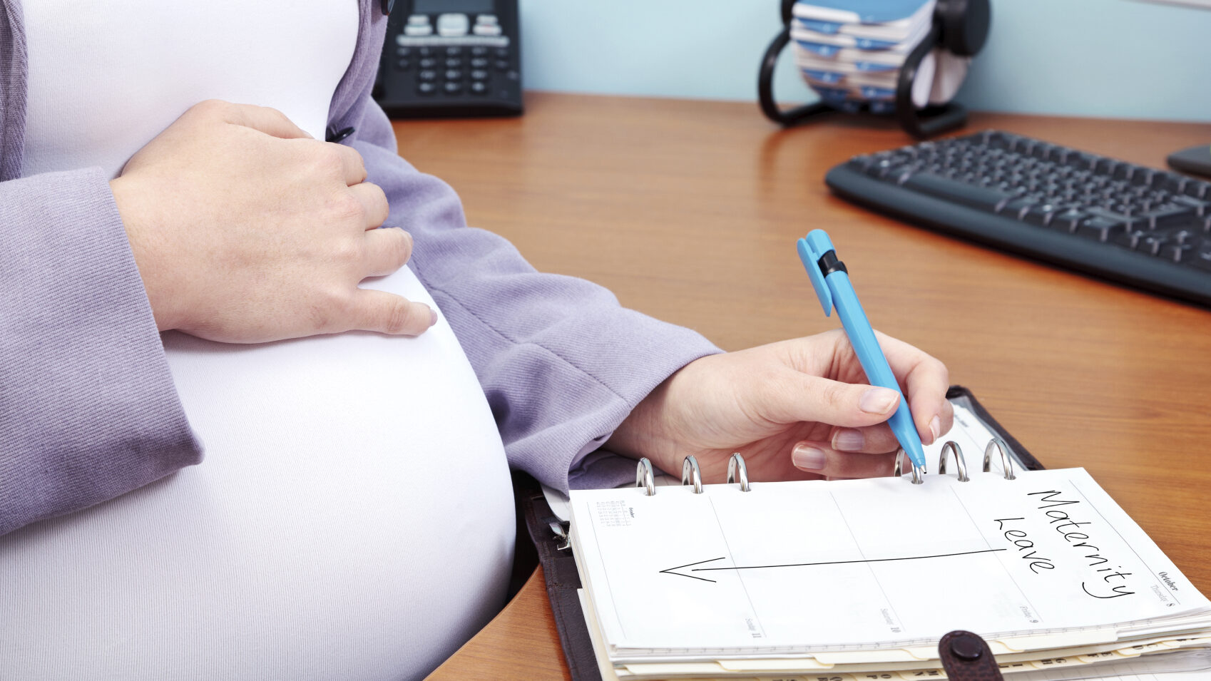 a pregnant woman writes on a paper, a new law seeks accommodations for pregnant workers...