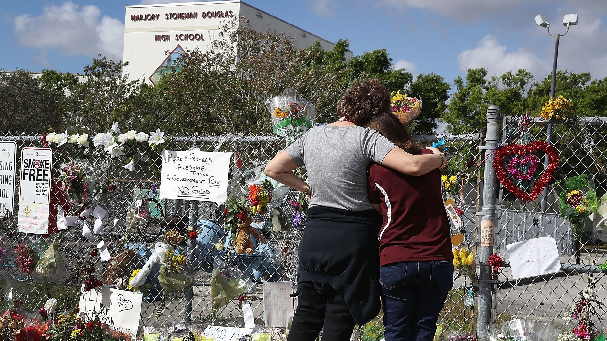 Two staff members view the memorial in front of Marjory Stoneman Douglas High School on February 23...