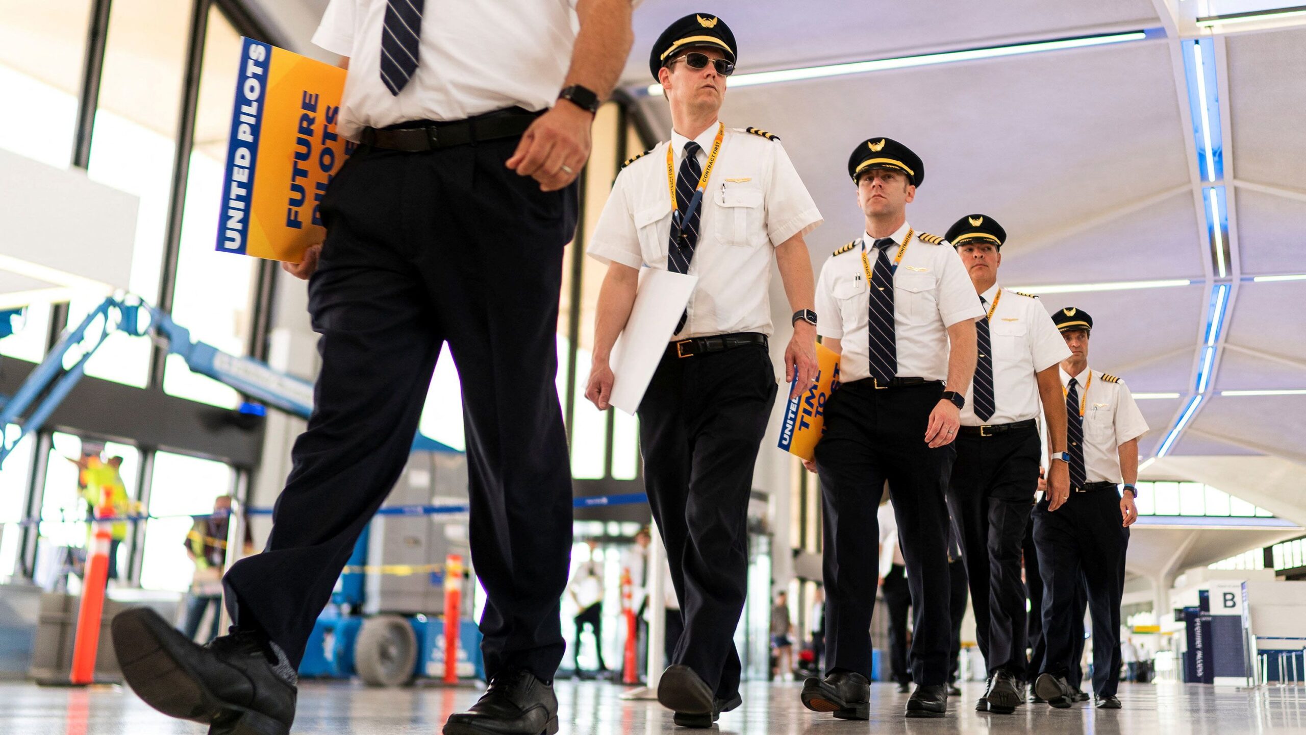 Pilots from United Airlines walk inside the airport as they take part in an informational picket at...