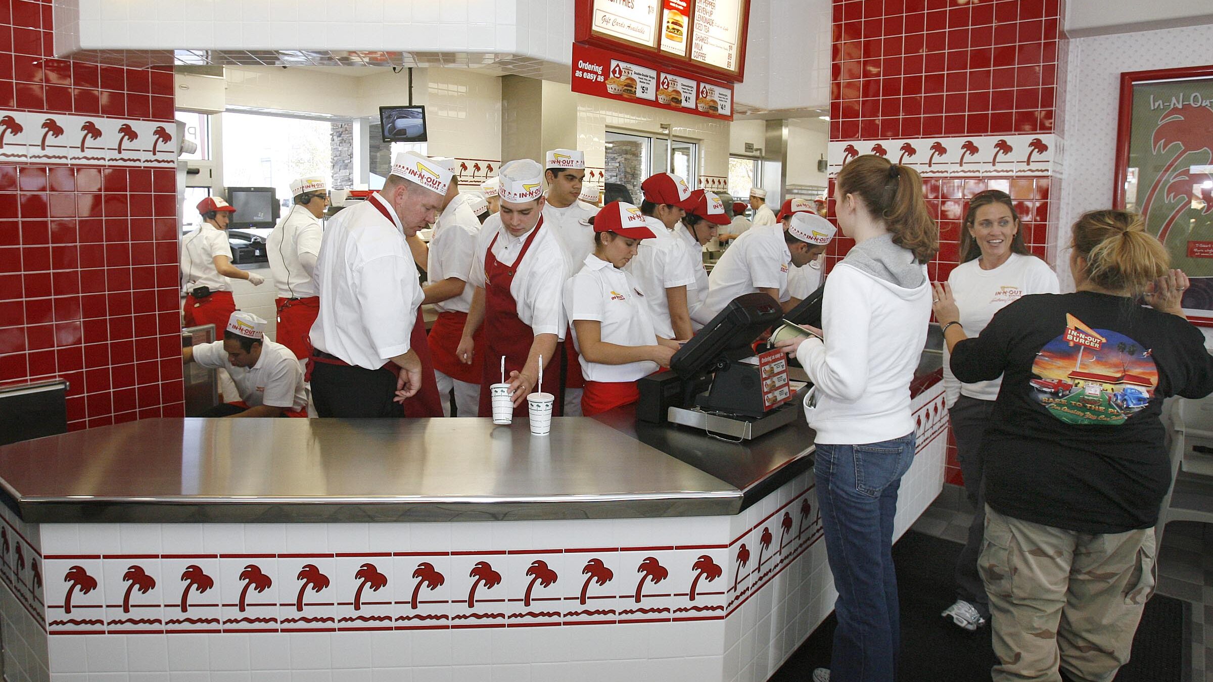 in-n-out workers serve customers at counter, the chain will ban masks for employees...