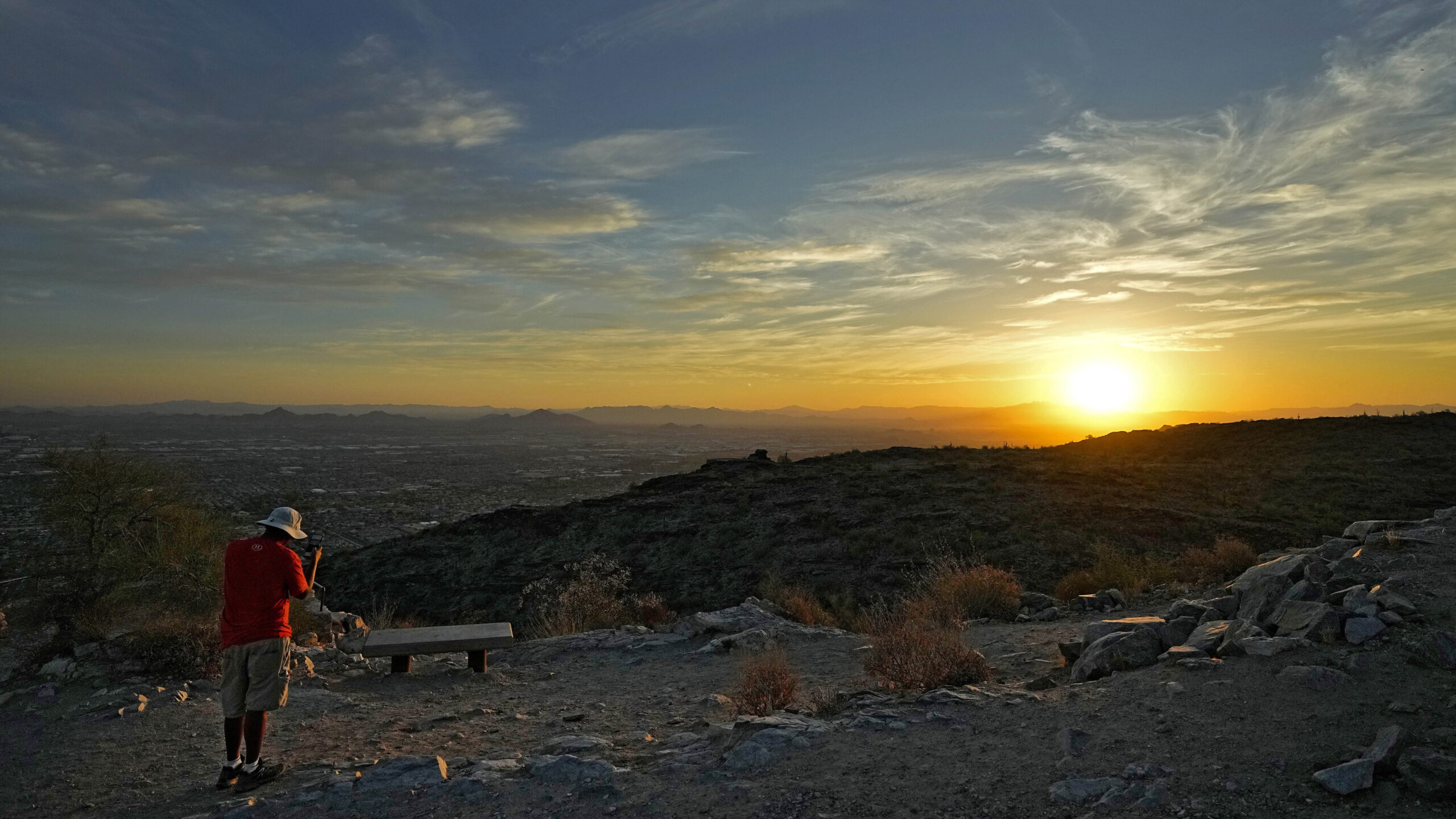 A hiker photographs the sun rising over the Valley atop South Mountain, Monday, July 17, 2023 Phoen...