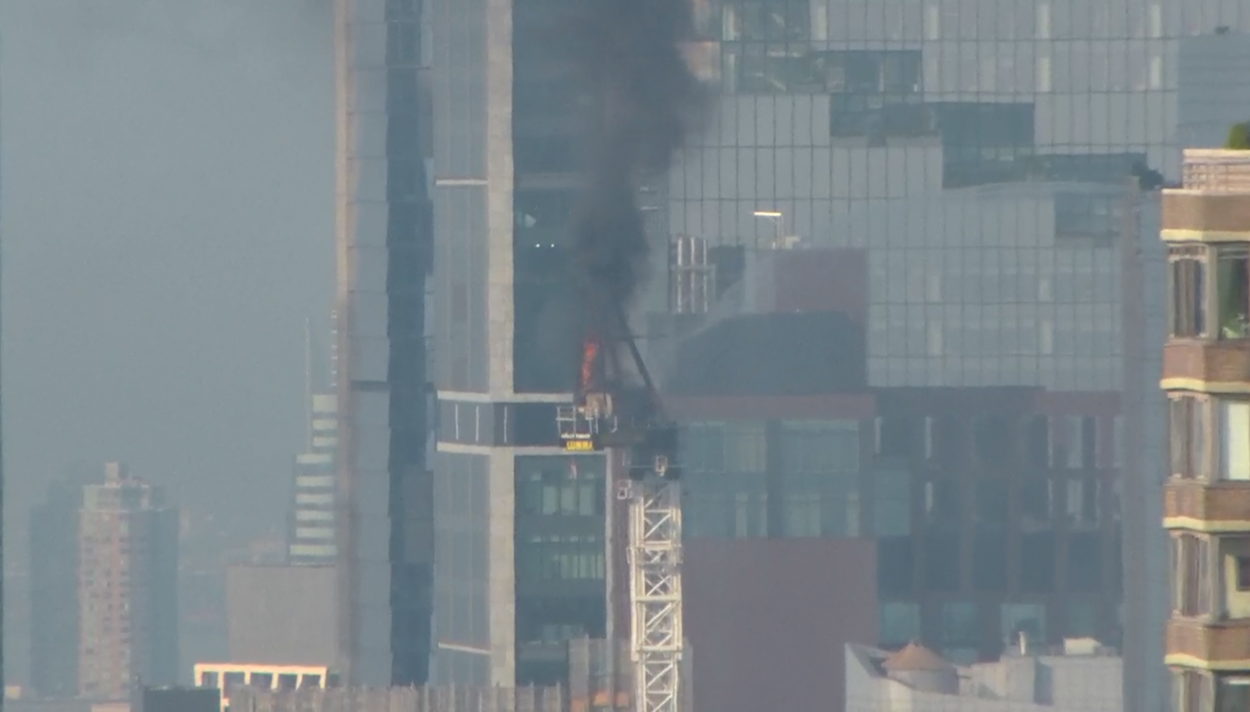 Emergency responders battle flames as a large construction crane caught fire in Manhattan on Wednes...