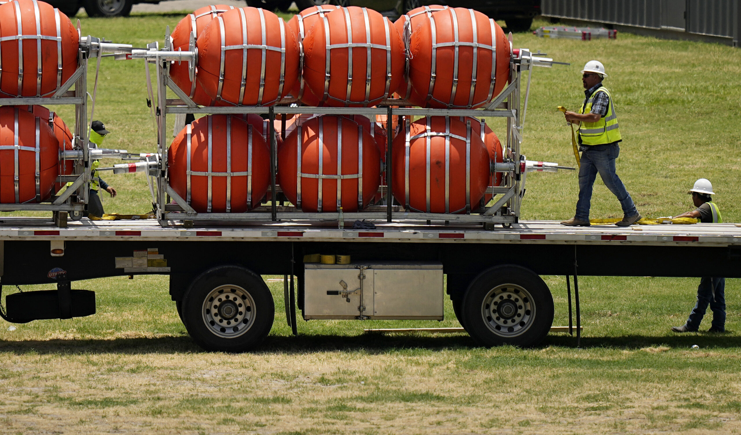 Dozens of large buoys that are set to be deployed in the Rio Grande are unloaded, Friday, July 7, 2...