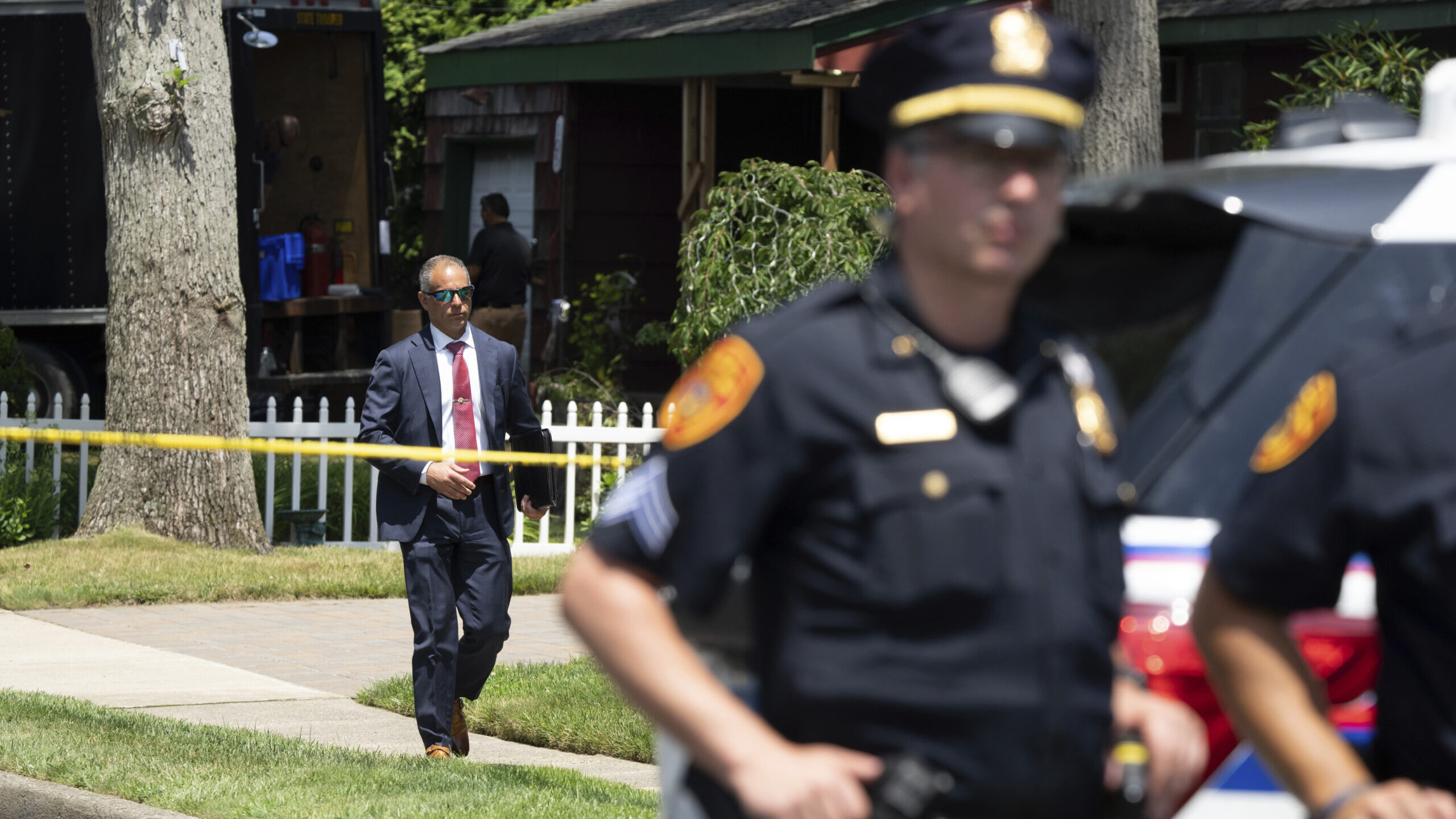 Police officers stand guard as law enforcement searches the home of Rex Heuermann, Saturday, July 1...