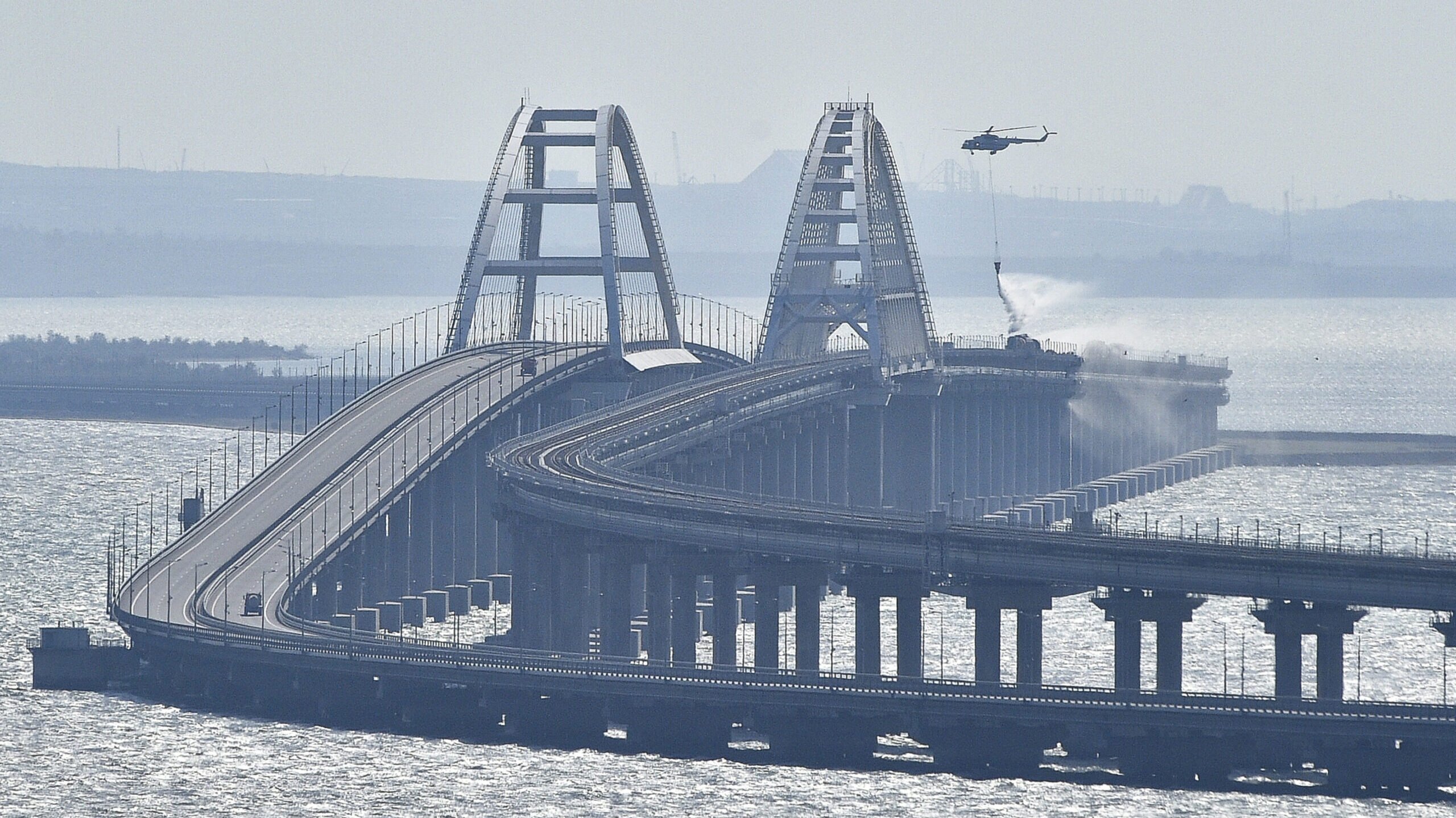 FILE - A helicopter drops water to stop fire on Crimean Bridge connecting Russian mainland and Crim...