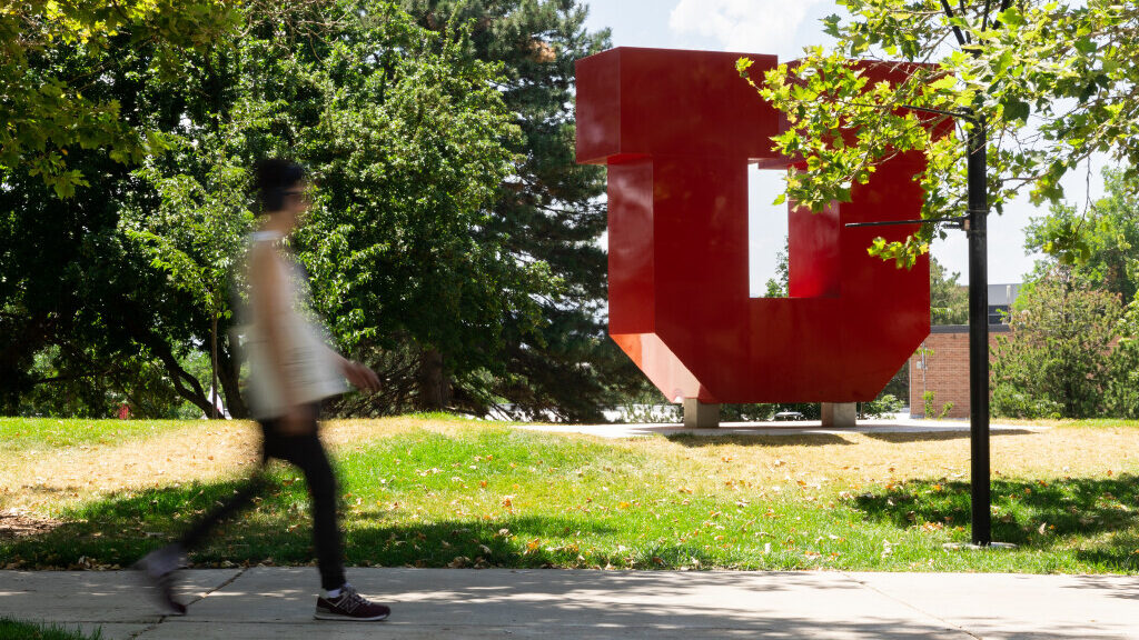 student at the university of utah walks past "U" statue...