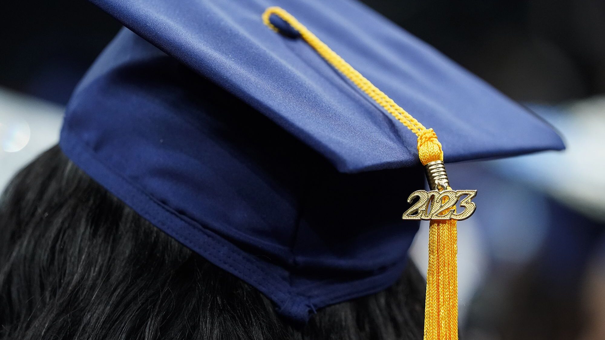 A tassel with 2023 on it rests on a graduation cap as students walk in a procession for Howard Univ...