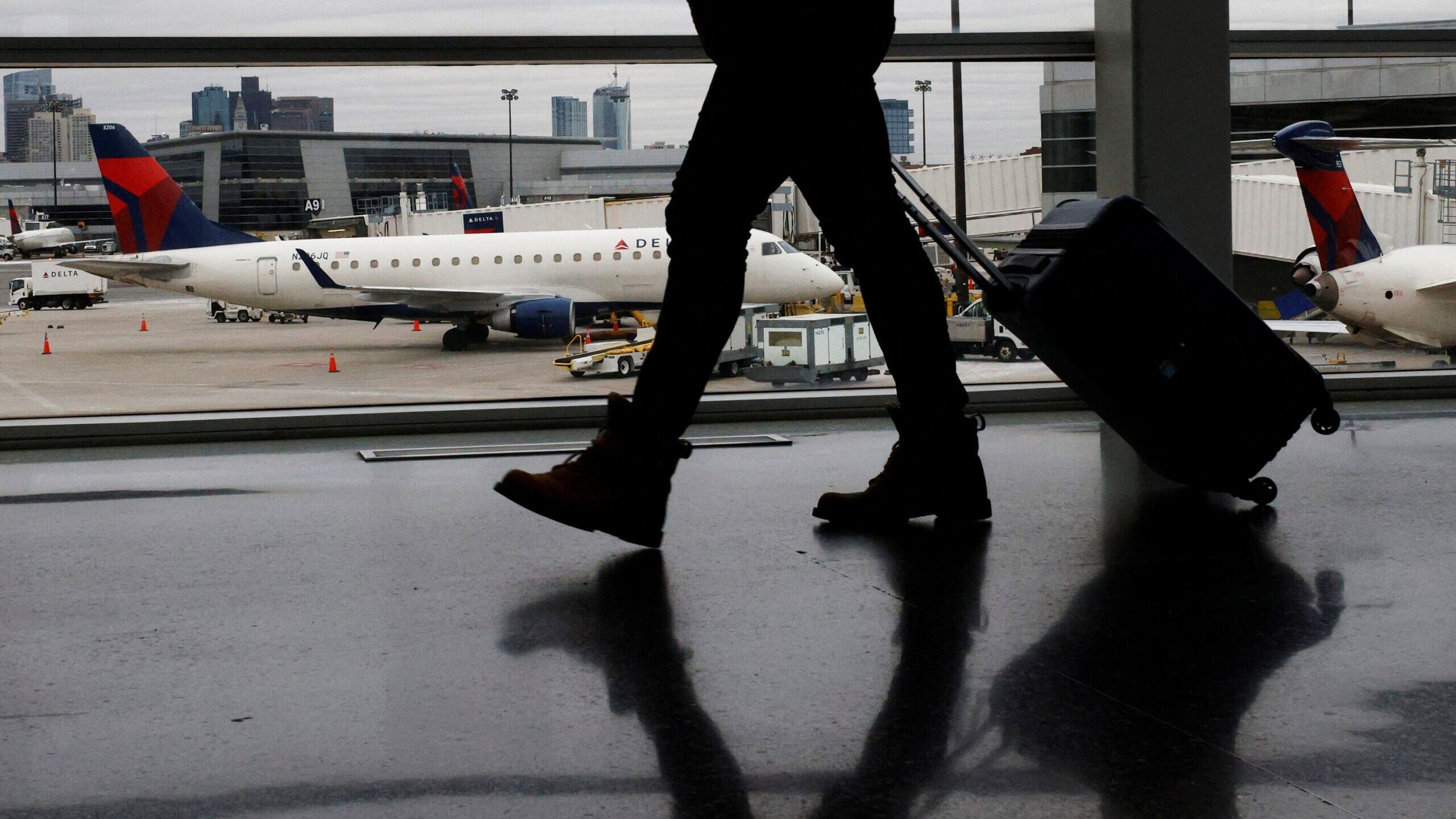 A passenger walks past a Delta Airlines plane at a gate at Logan International Airport in Boston, M...