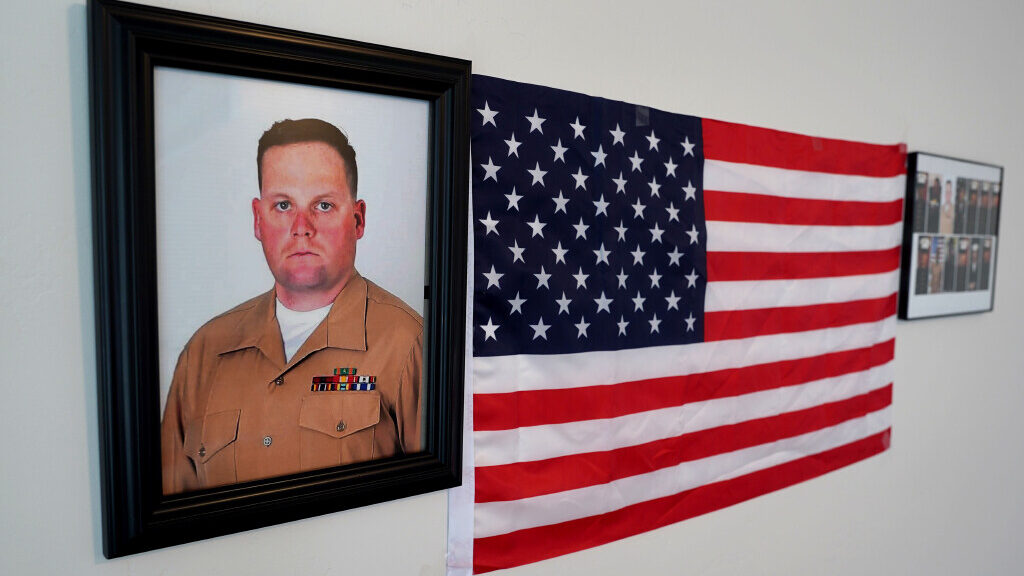 A framed picture of slain U.S. Marine Staff Sgt. Taylor Hoover hangs next to an American flag....