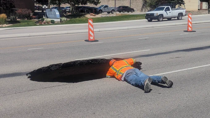A worker examines the damage of a sinkhole that formed in the middle lane of the eastbound lanes of...