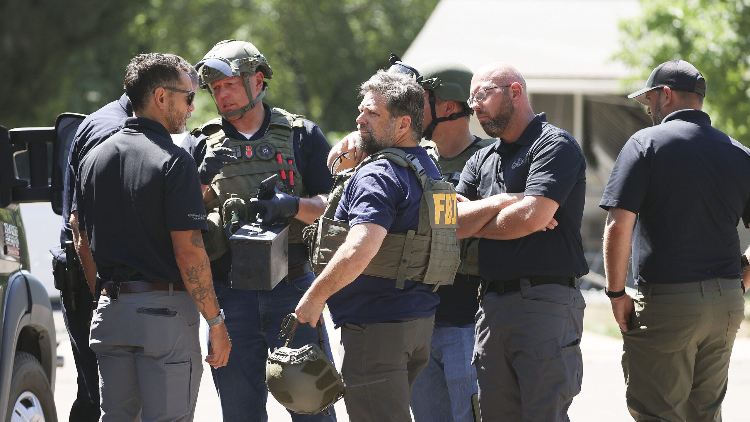 Law enforcement agents confer at the home of Craig Deeleuw Robertson who was shot and killed by FBI...