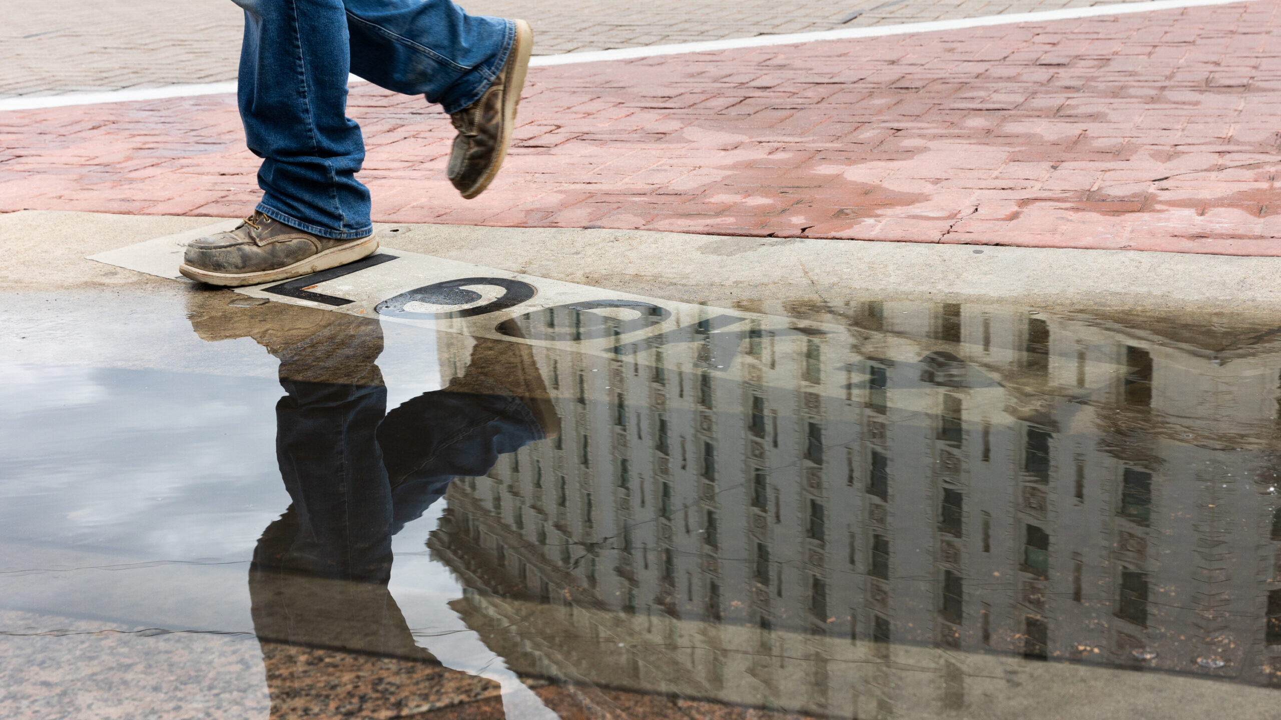 A puddle left by the rain reflects someone walking in downtown Salt Lake City on Tuesday, Aug. 22, ...