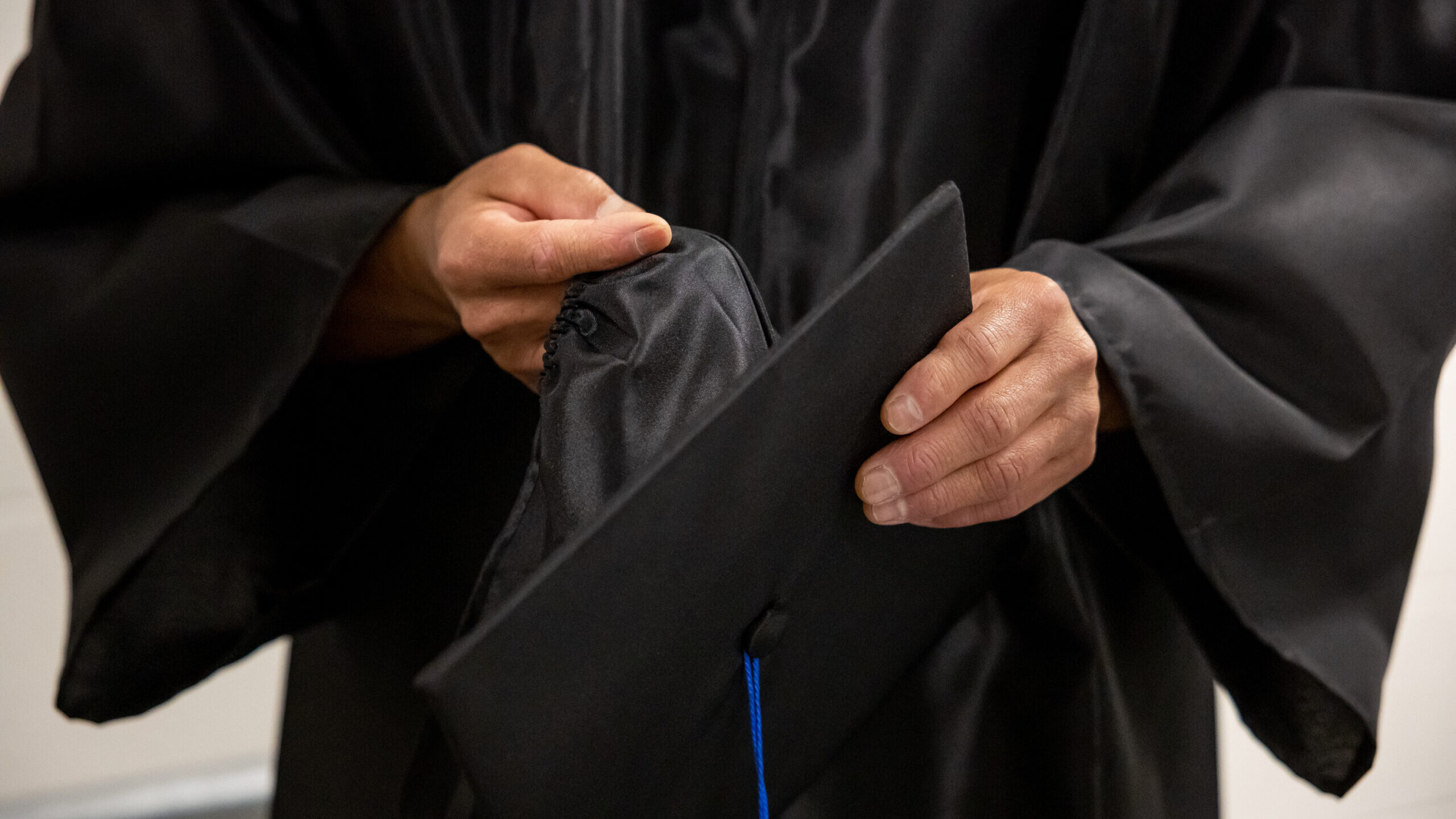 a man holds his cap during his graduation through the slcc prison education program...