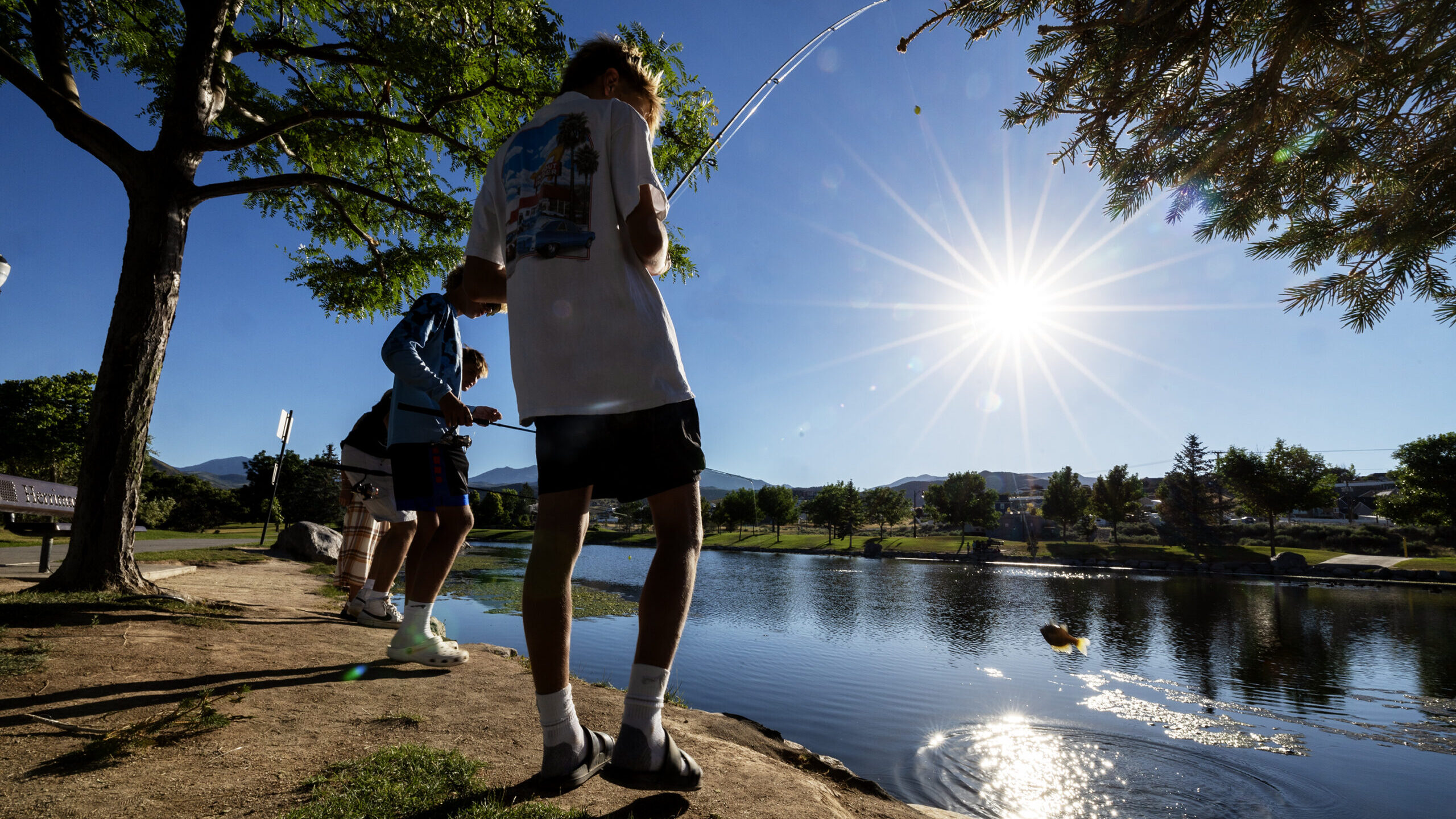 Image of two young men fishing at Cove Pond in Herriman, Utah. July 2023 marked the third-hottest J...