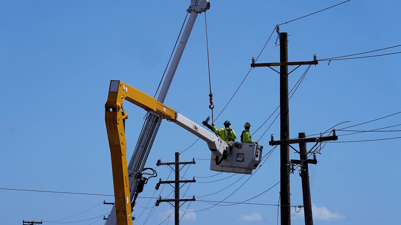 Linemen work on poles in Lahaina, Hawaii, following a deadly wildfire, on August 13. Hawaiian Elect...