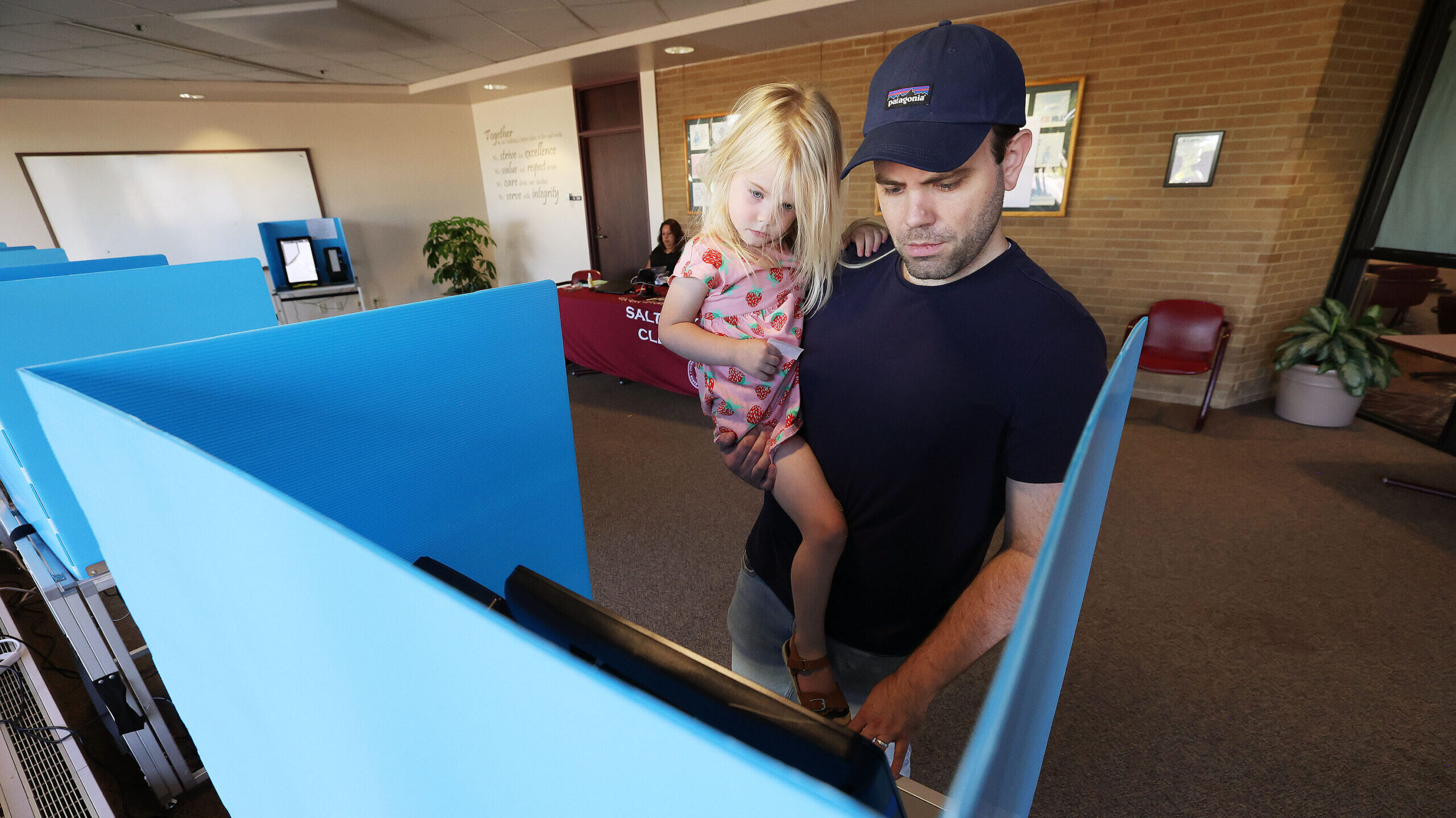 Andrew Roth holds his daughter Maggie as he casts his ballot during Utah's municipal and primary el...