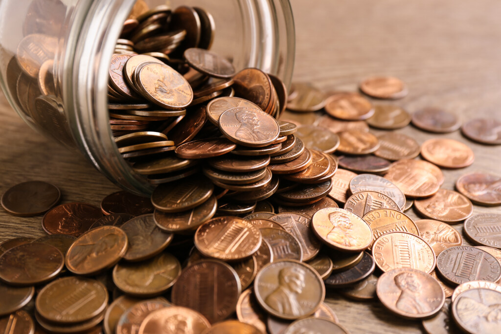 FILE - Glass jar with coins on table, closeup. (Adobe Stock)...