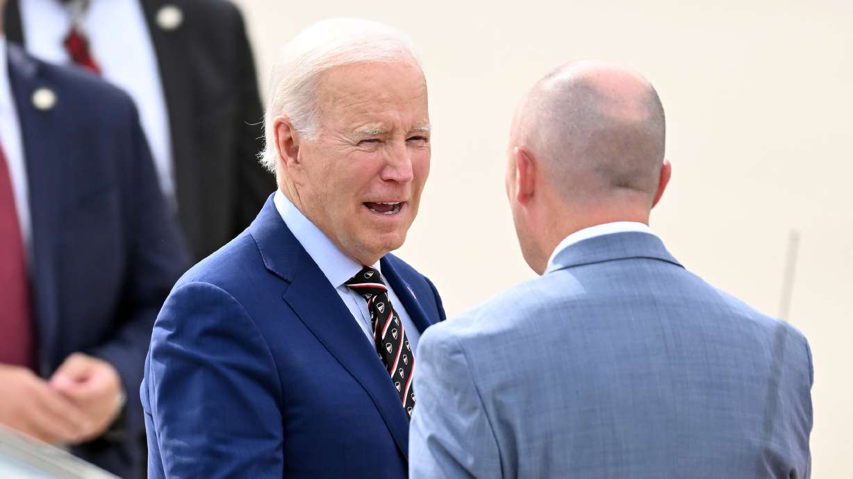 President Joe Biden talks with Gov. Spencer Cox after his arrival on Air Force One in Salt Lake Cit...