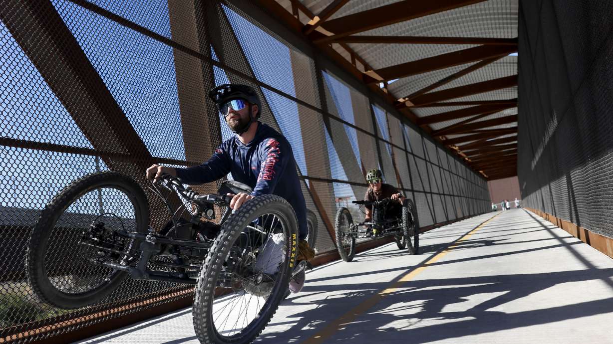 Hand cyclists pedal across a bridge over the Jordan River section of Parley's Trail in West Valley ...