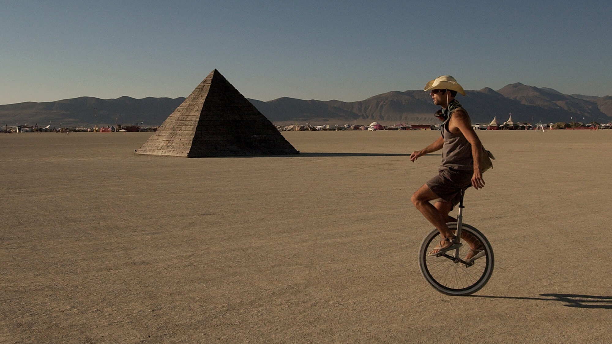 A unicyclist rides past a pyramid on the playa during Burning Man at Black Rock Desert in Nevada, w...