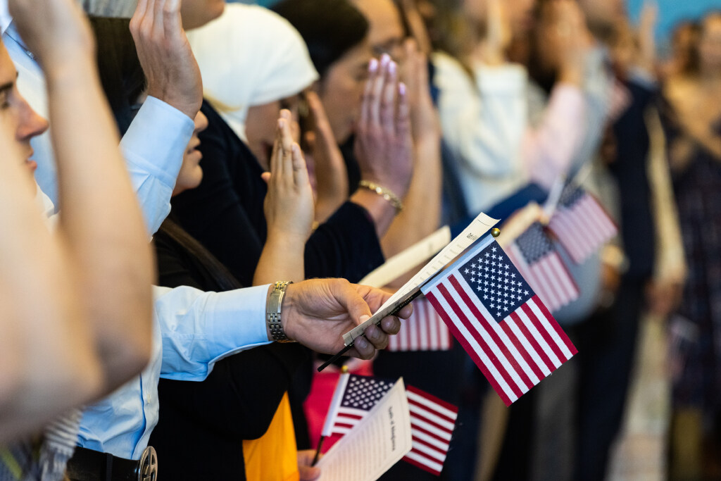 Candidates for U.S. citizenship raise their right hands and take an oath of allegiance during their...