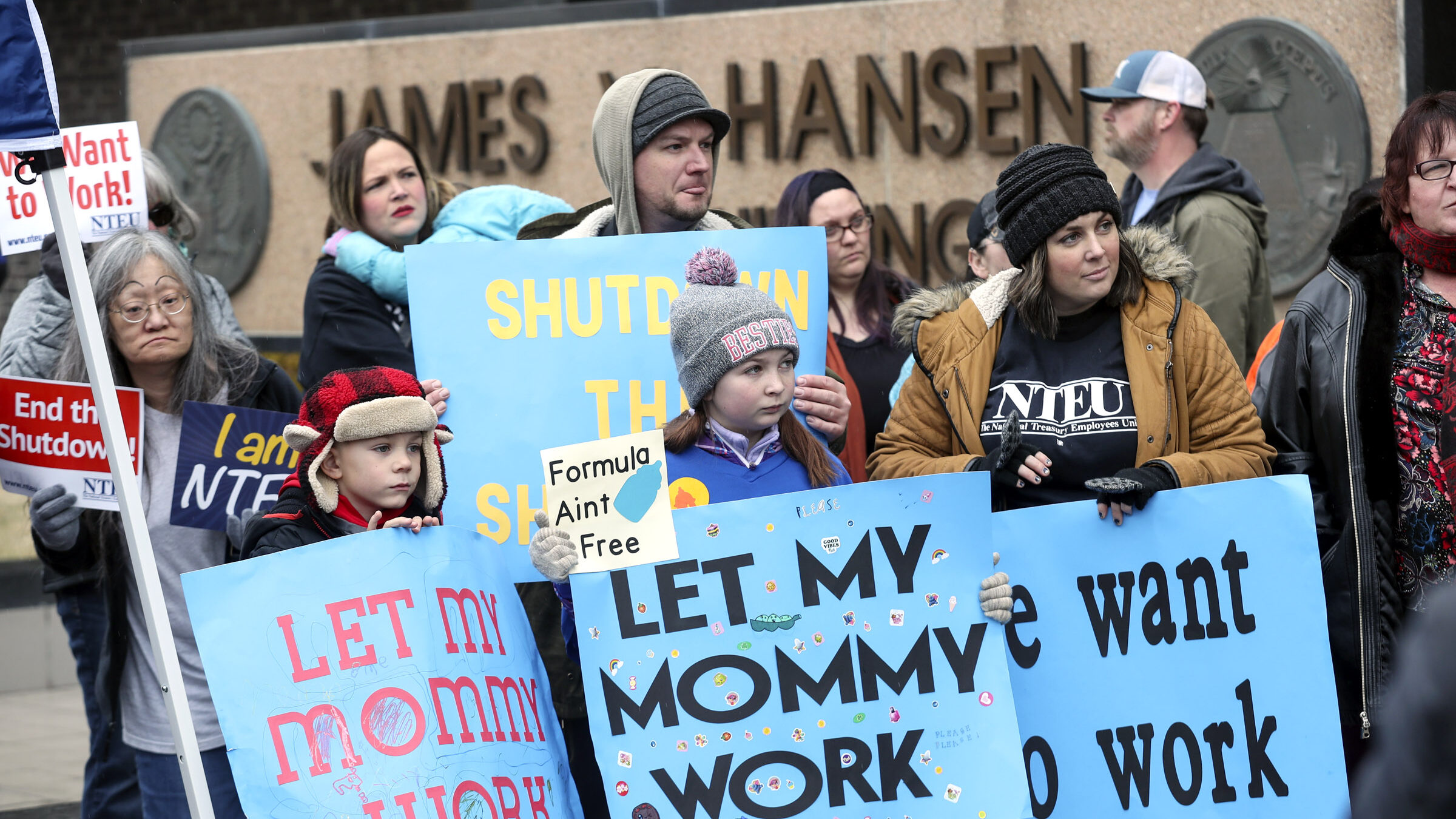 irs and other government employees and their families hold protest signs about the government shutd...