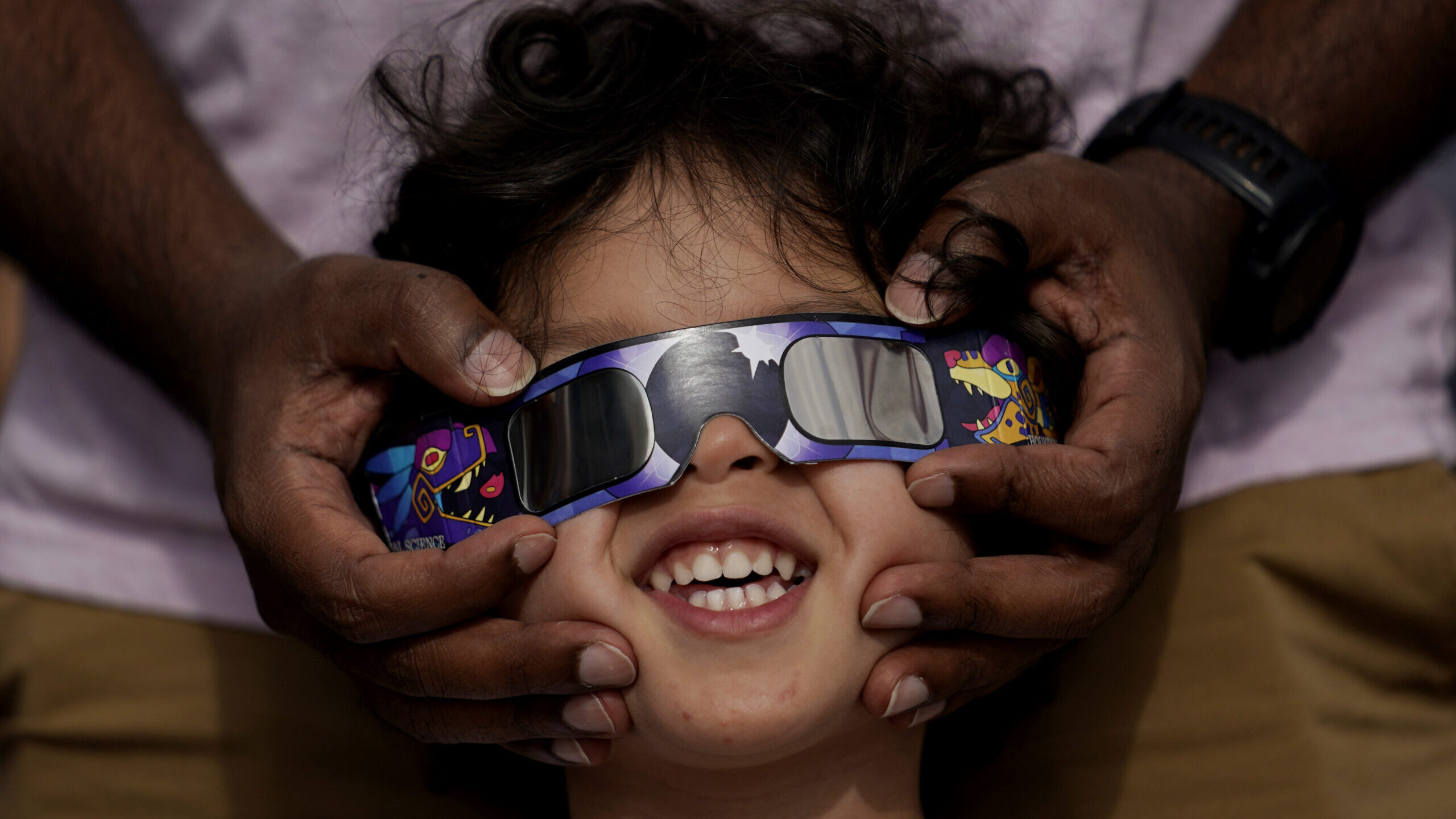 Viewers use special glasses to watch from San Antonio, as the moon moves in front of the sun during...