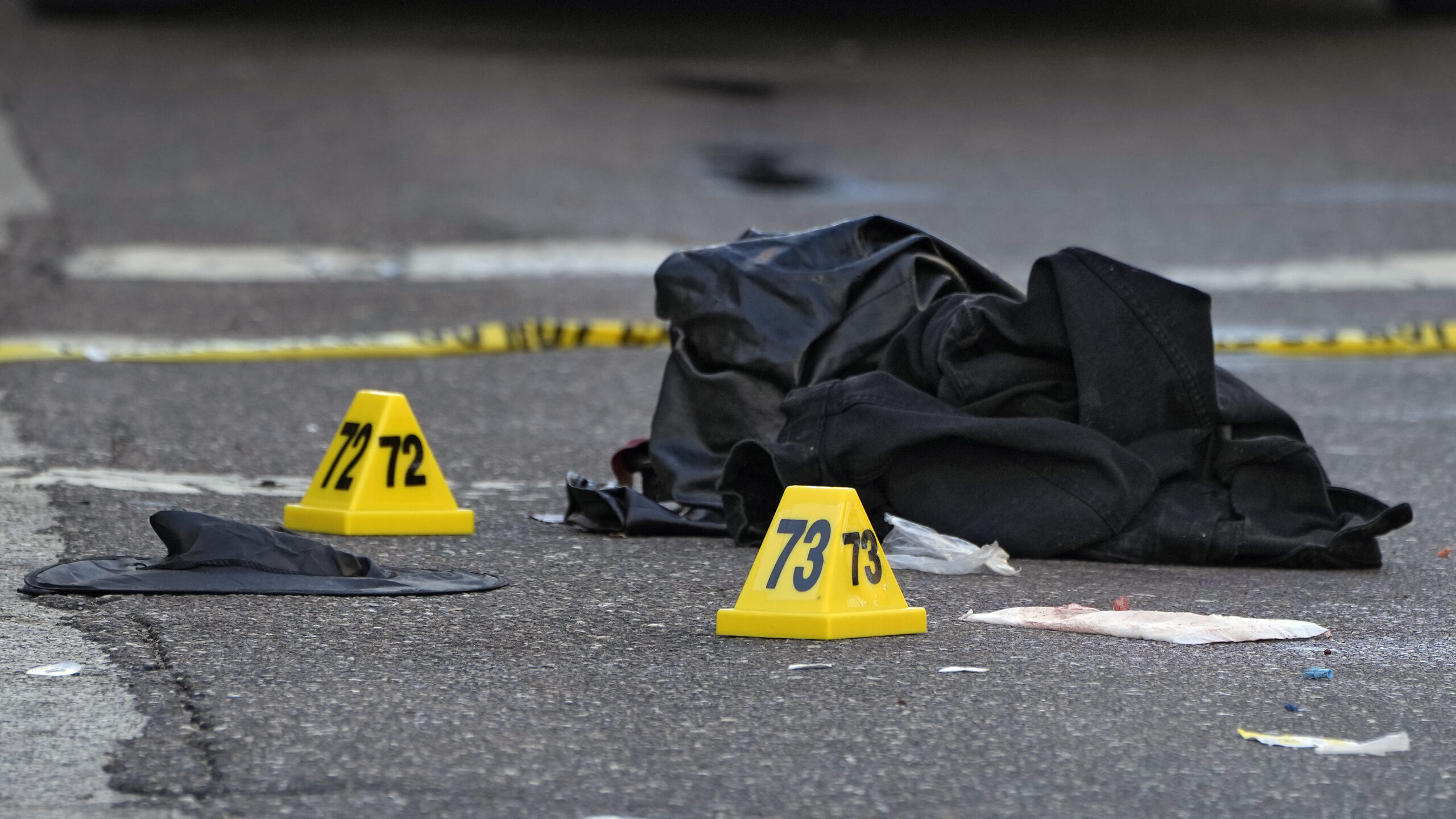 A witch hat, left, and an unidentified object are shown in the street near evidence markers in the ...