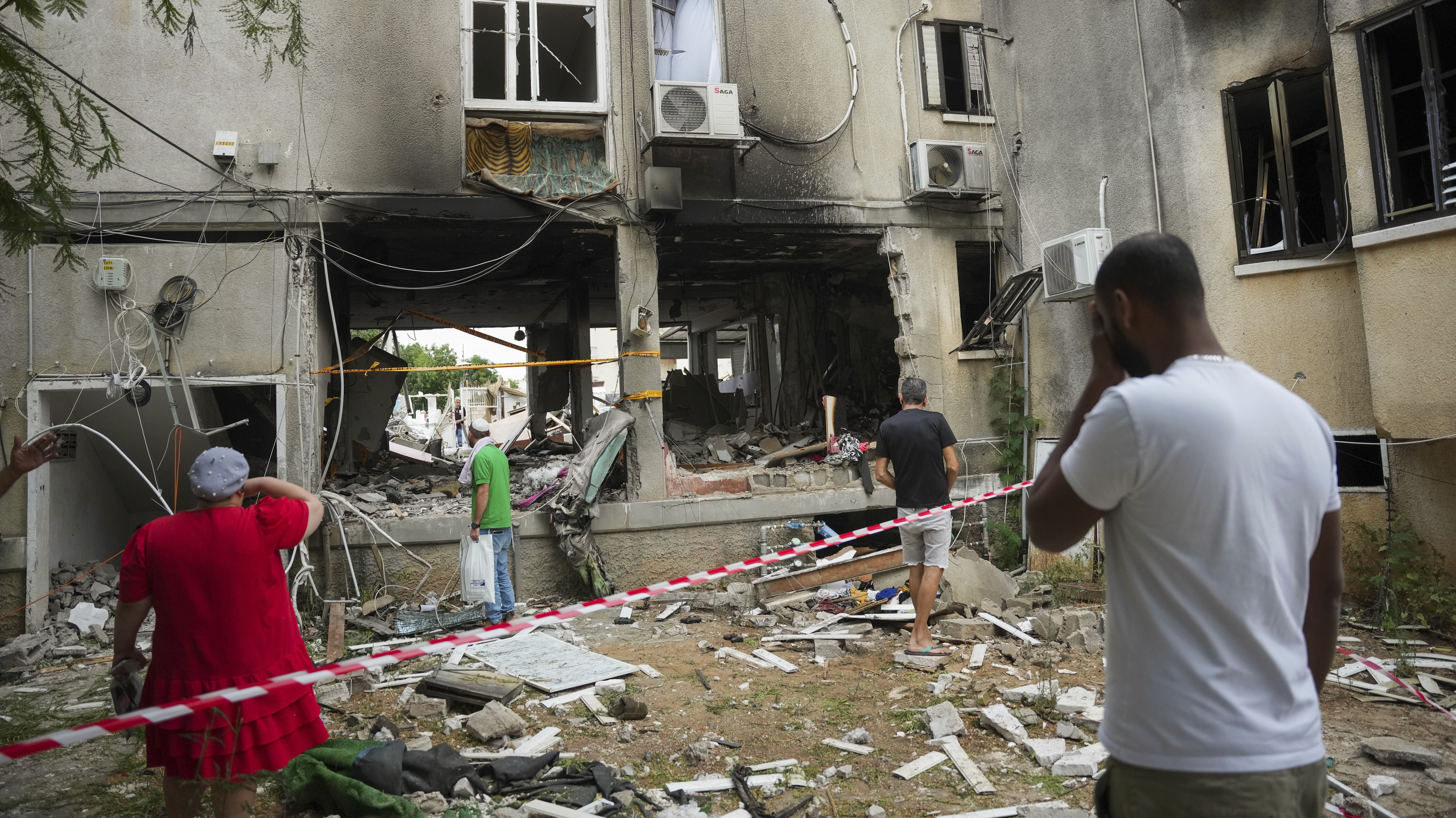 people look through damaged buildings in israel...