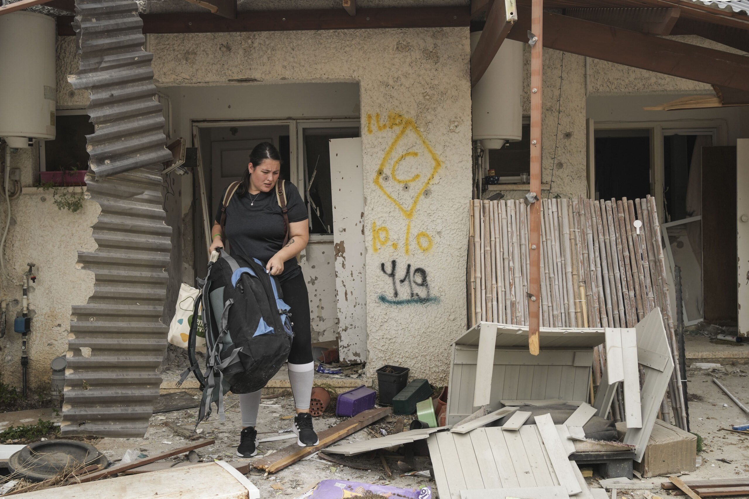 A woman recovers items from a house damaged during the Hamas attack in Kibbutz Kfar Azza, Israel. T...