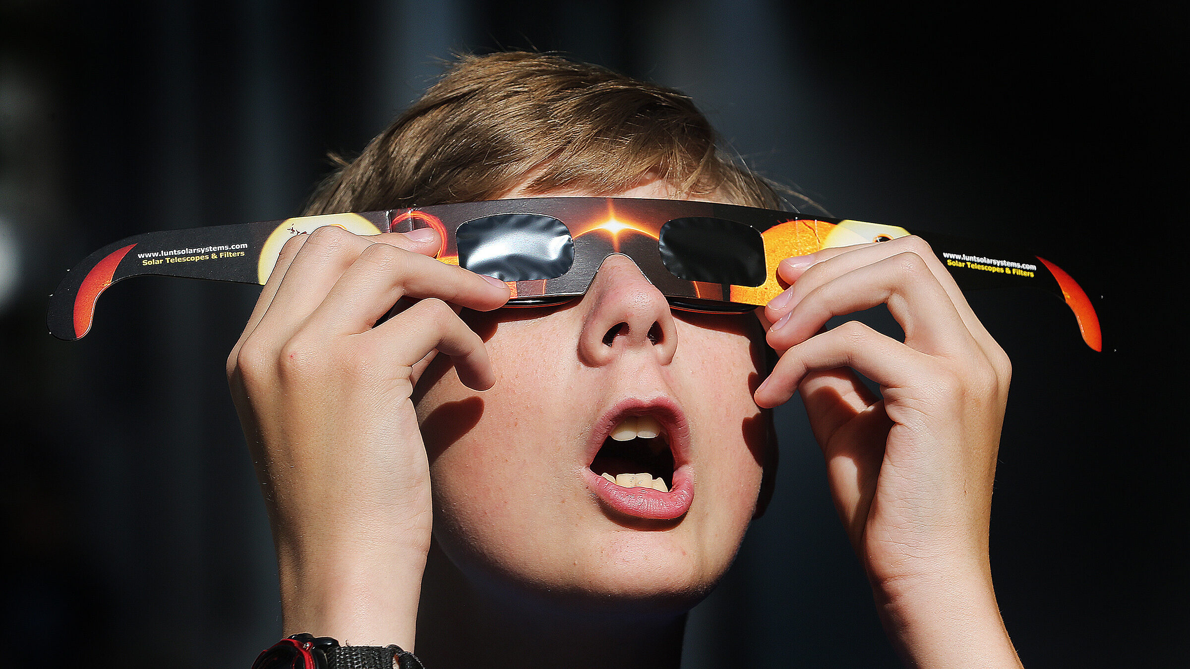 Boy tries out his new eclipse glasses he just bought from Clark Planetarium in preparation for the ...