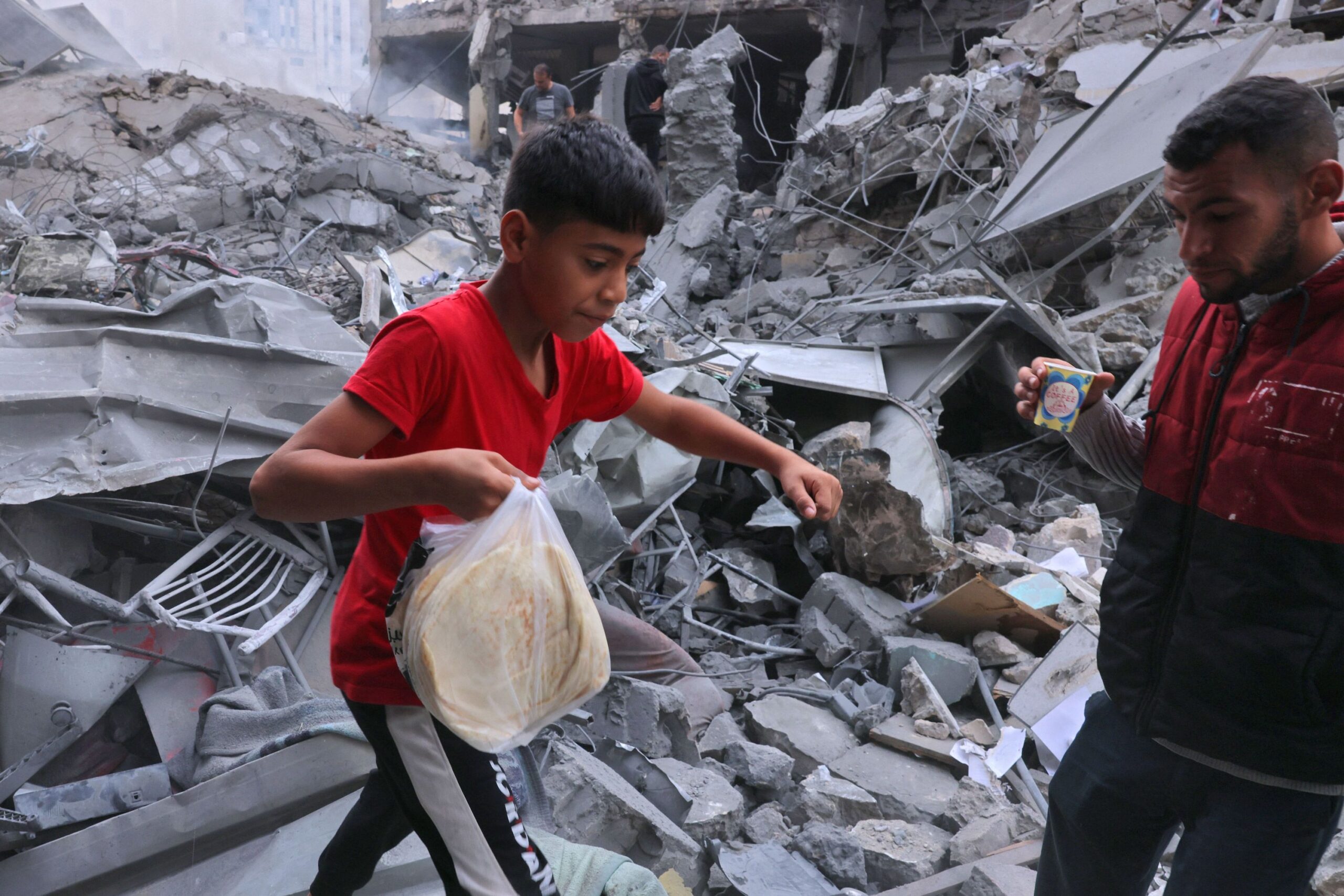 A Palestinian youth carries bread amid the rubble of the city center of Khan Yunis in the southern ...