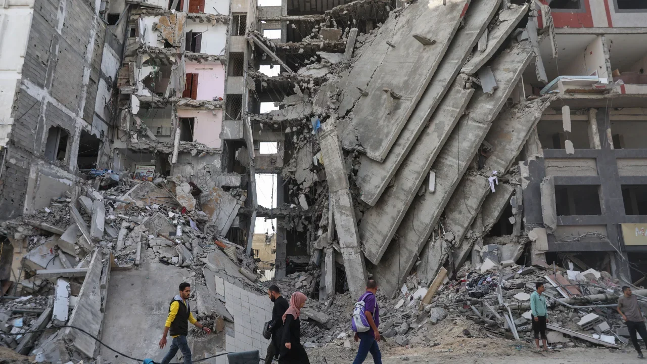 Palestinians walk through damaged buildings in Gaza City....
