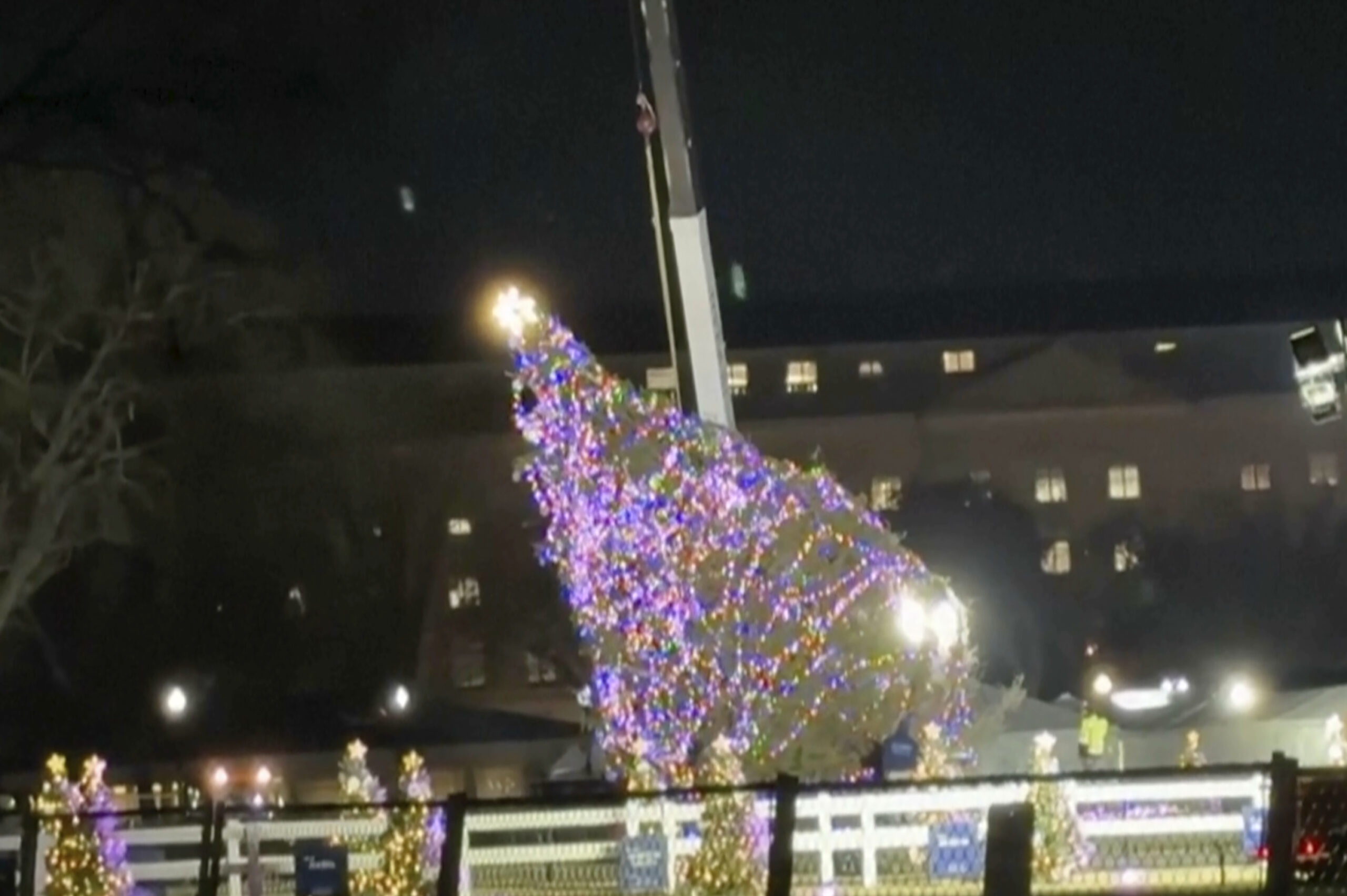 In this image made from video, the National Christmas Tree hangs from a crane in front of the White...