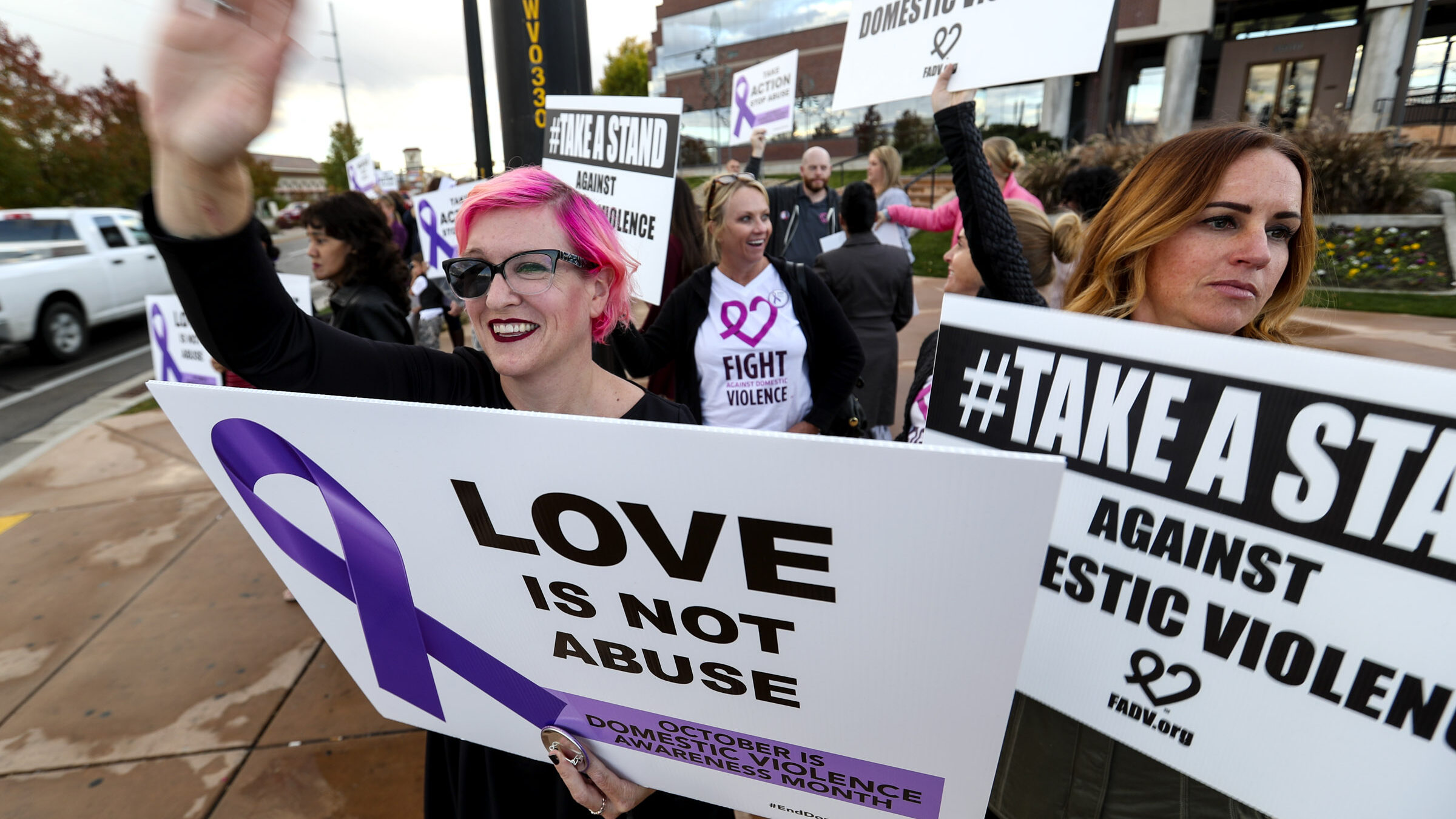 advocates hold up signs supporting domestic violence victims - SALT LAKE CITY -- The new domestic v...