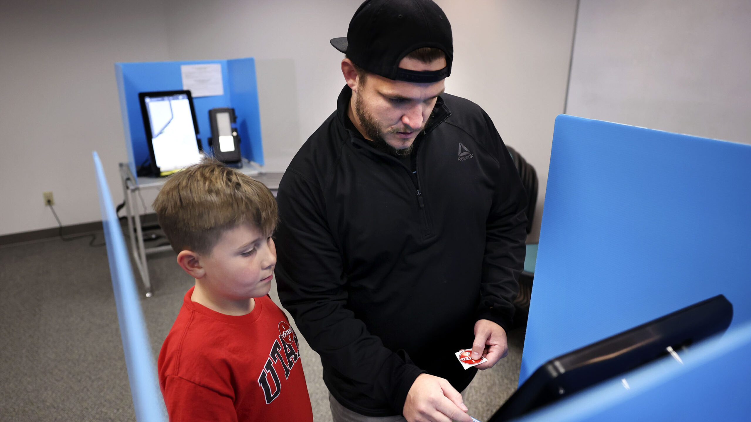 Cooper Brannon, 8, watches his father, Austin, vote at the Salt Lake County Government Center in Sa...