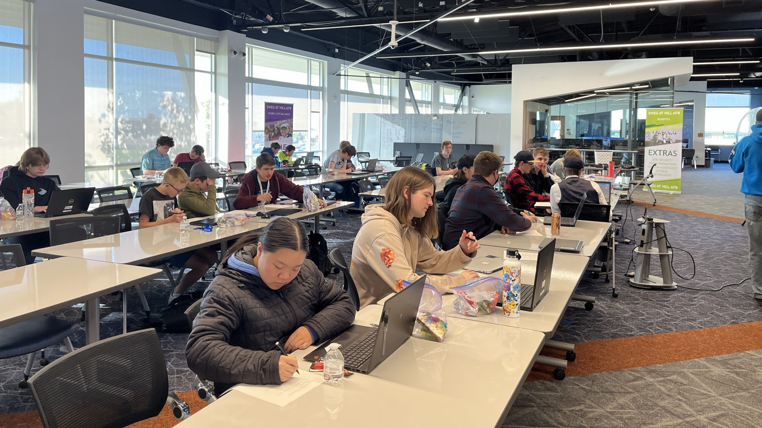 students sit at their computers as they compete in a hackathon...