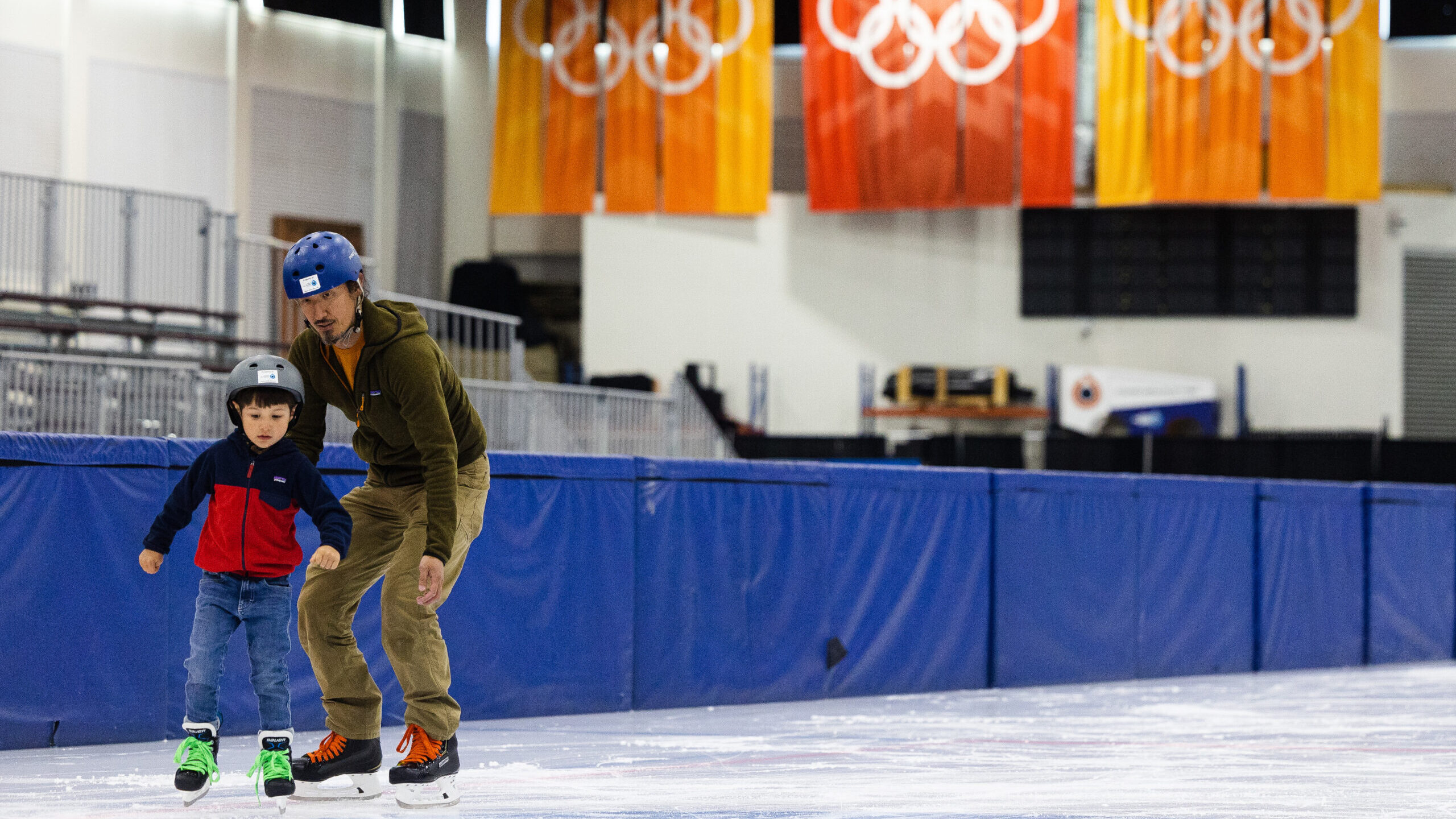 an adult and child skate together at the olympic oval built for the 2002 salt lake games...